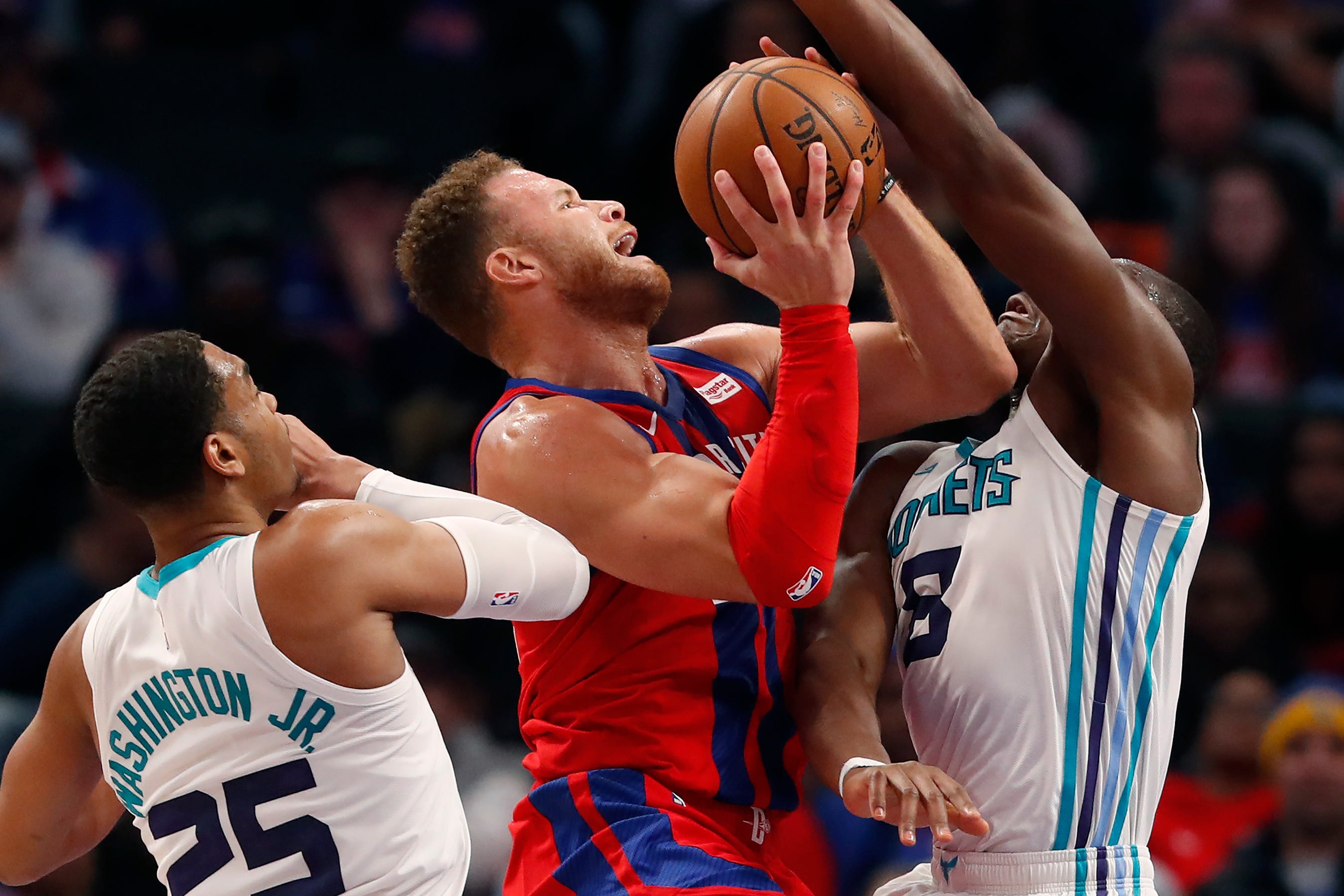 Pistons forward Blake Griffin attempts a shot between the defense of Hornets forward PJ Washington (25) and center Bismack Biyombo.