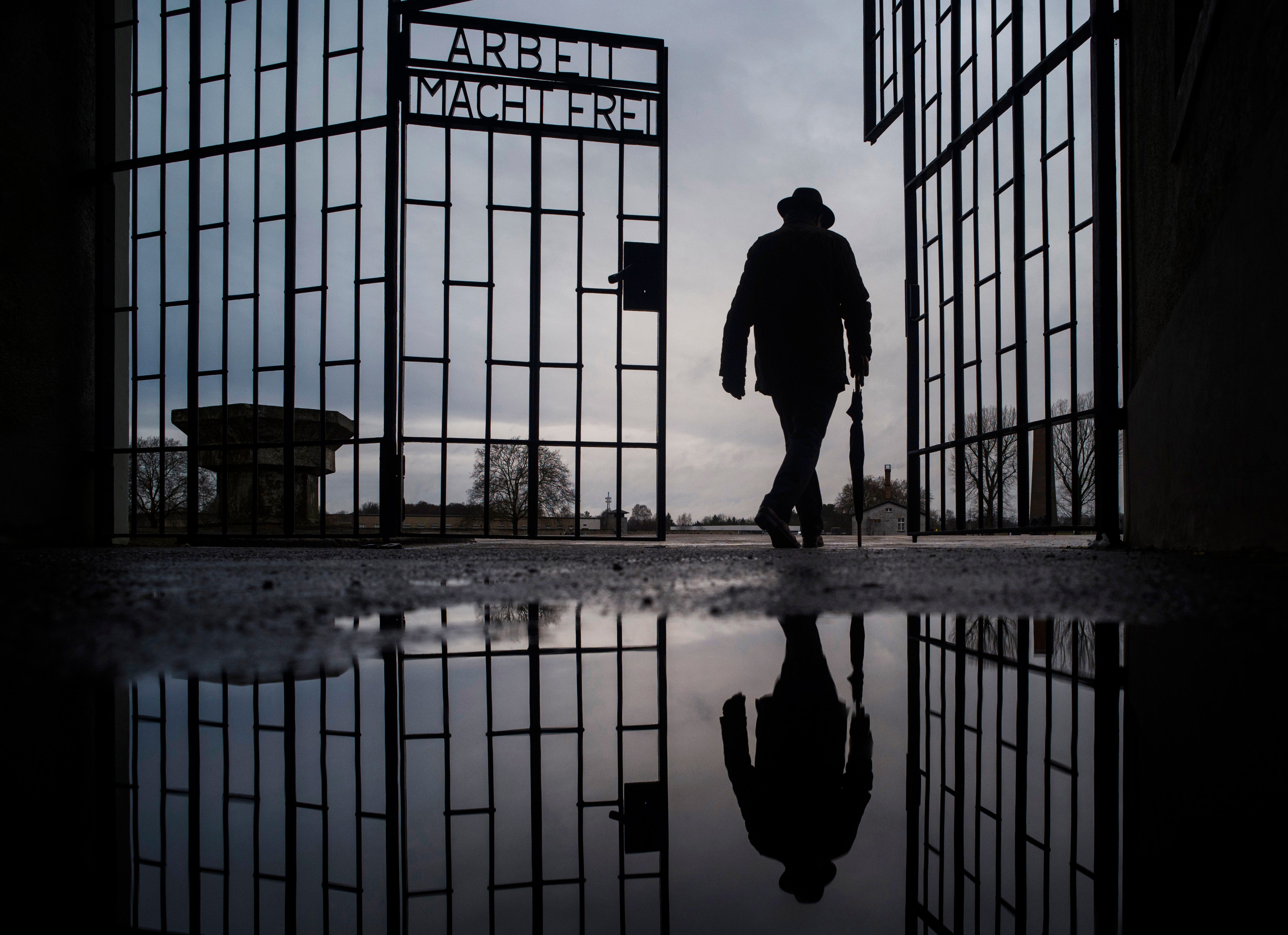 A man walks through the gate of the Sachsenhausen Nazi death camp with the phrase "Arbeit macht frei" (work sets you free) in Oranienburg, Germany, on International Holocaust Remembrance Day, Jan. 27, 2019.