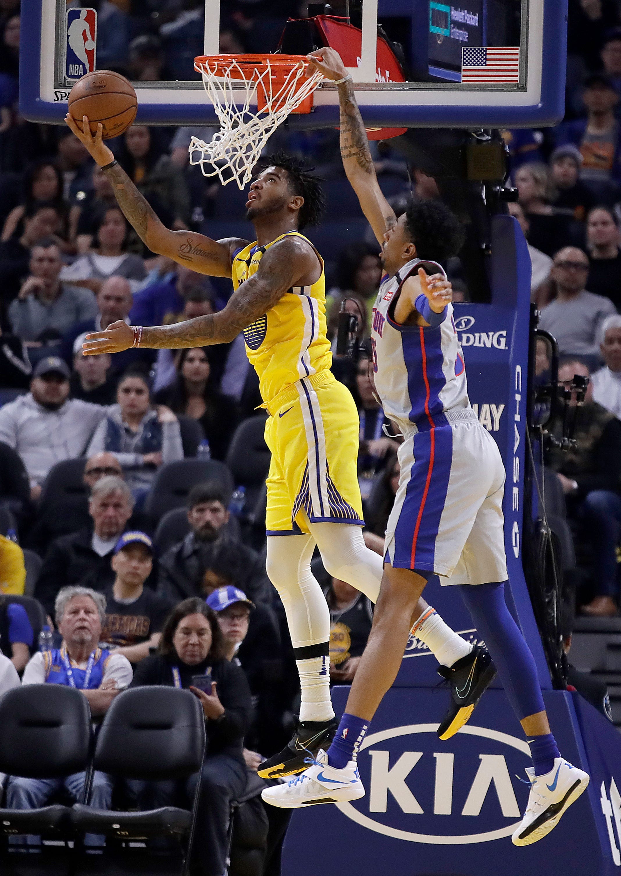 Golden State Warriors' Marquese Chriss, left, lays up a shot against Detroit Pistons' Christian Wood during the first half.