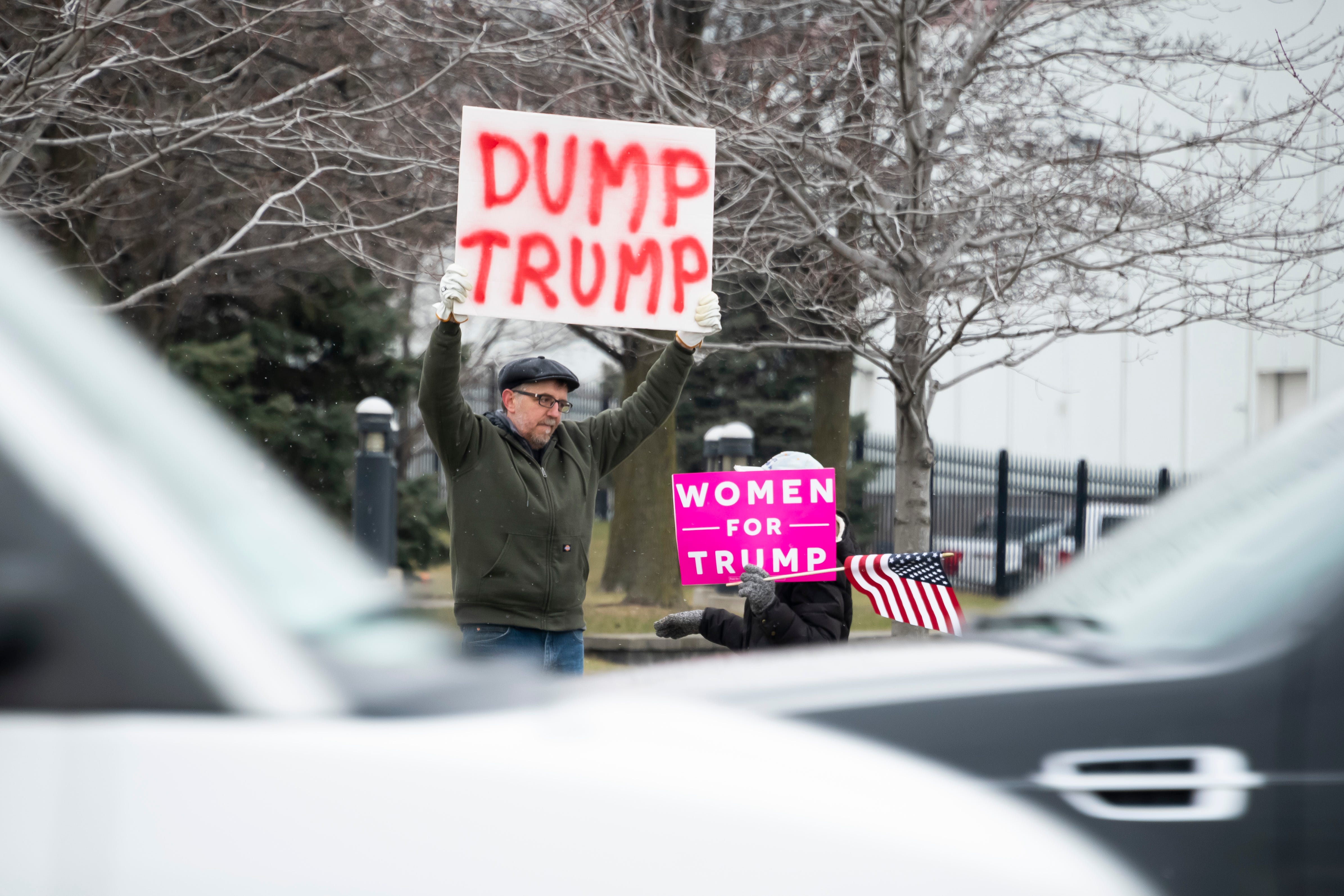 Ken Planet of Sterling Heights and Tammie Schwartz of Macomb Township display opposing viewpoints while awaiting the arrival of  President Donald Trump along Van Dyke.