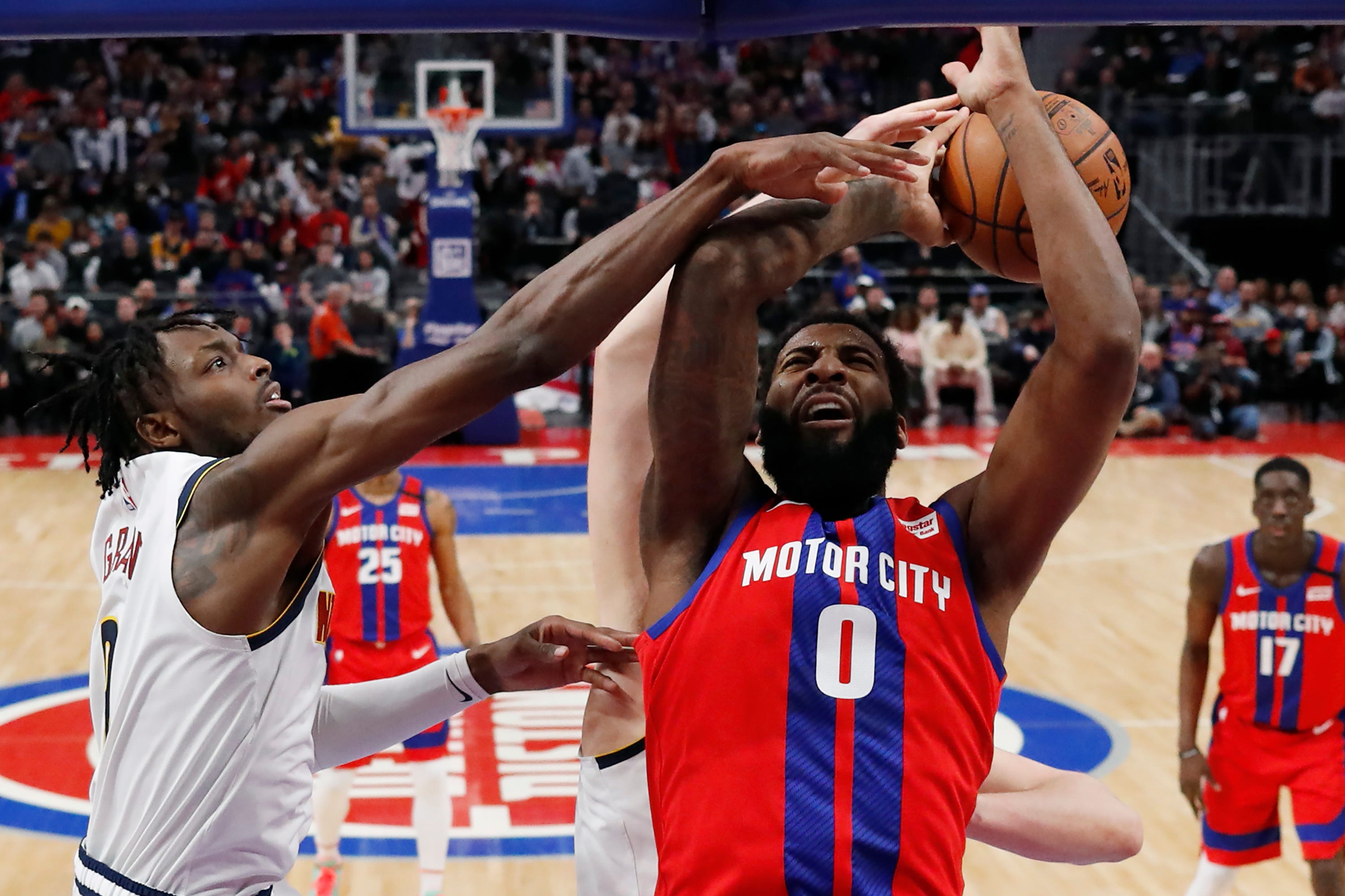 Denver Nuggets forward Jerami Grant, left, reaches in as teammate center Nikola Jokic knocks the ball away from Detroit Pistons center Andre Drummond (0) during the first half.