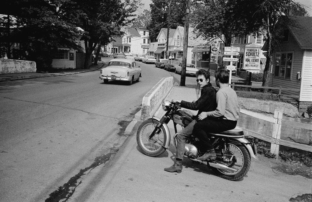 Bob Dylan drives his Triumph Motorcycle with John Sebastian riding along in Woodstock, NY, 1964 .