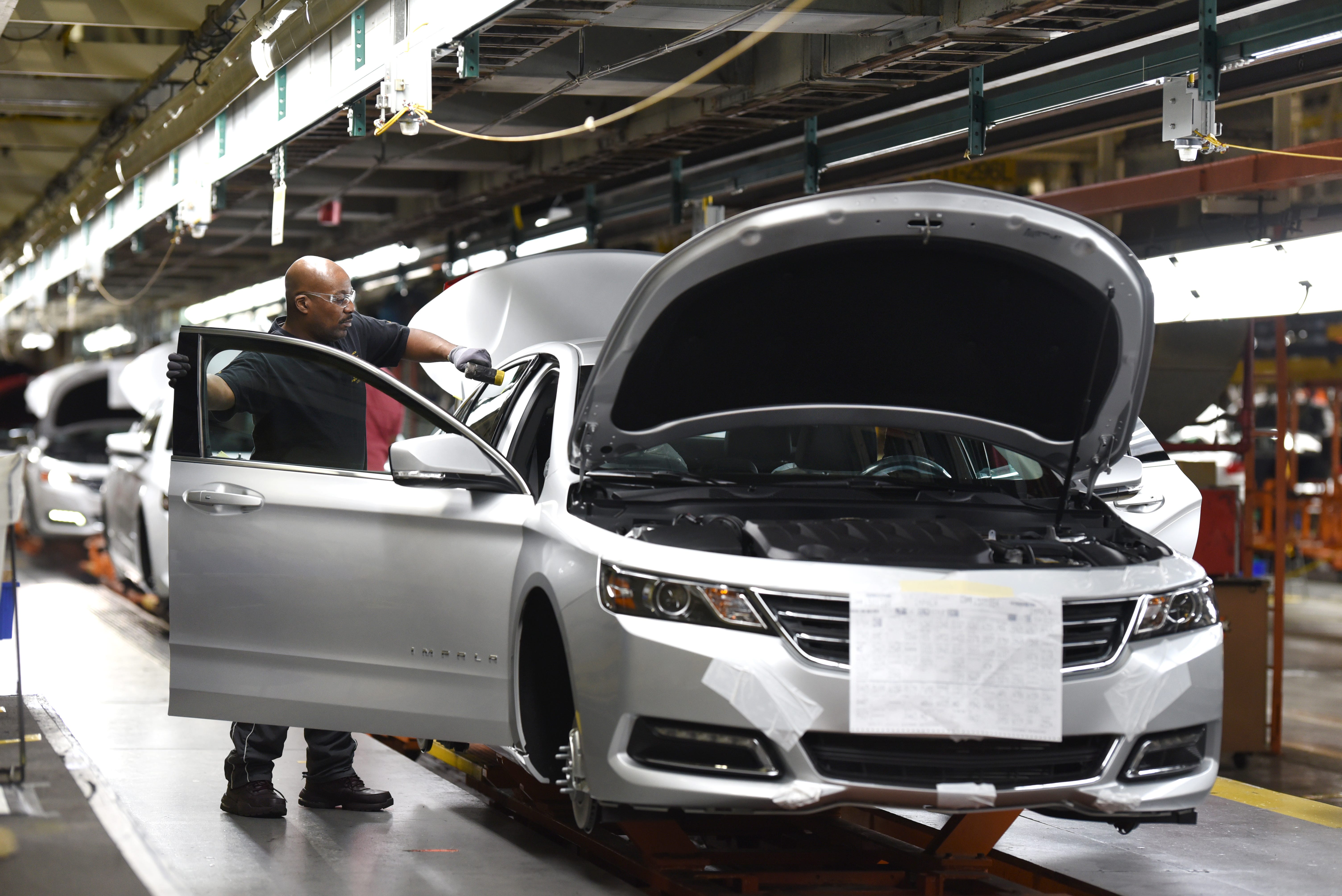 An assembly line worker at the General Motors Detroit-Hamtramck plant inspects the fit and finish of the Chevrolet Impala built at the facility as the plant will be converting from internal-combustion production to EV.