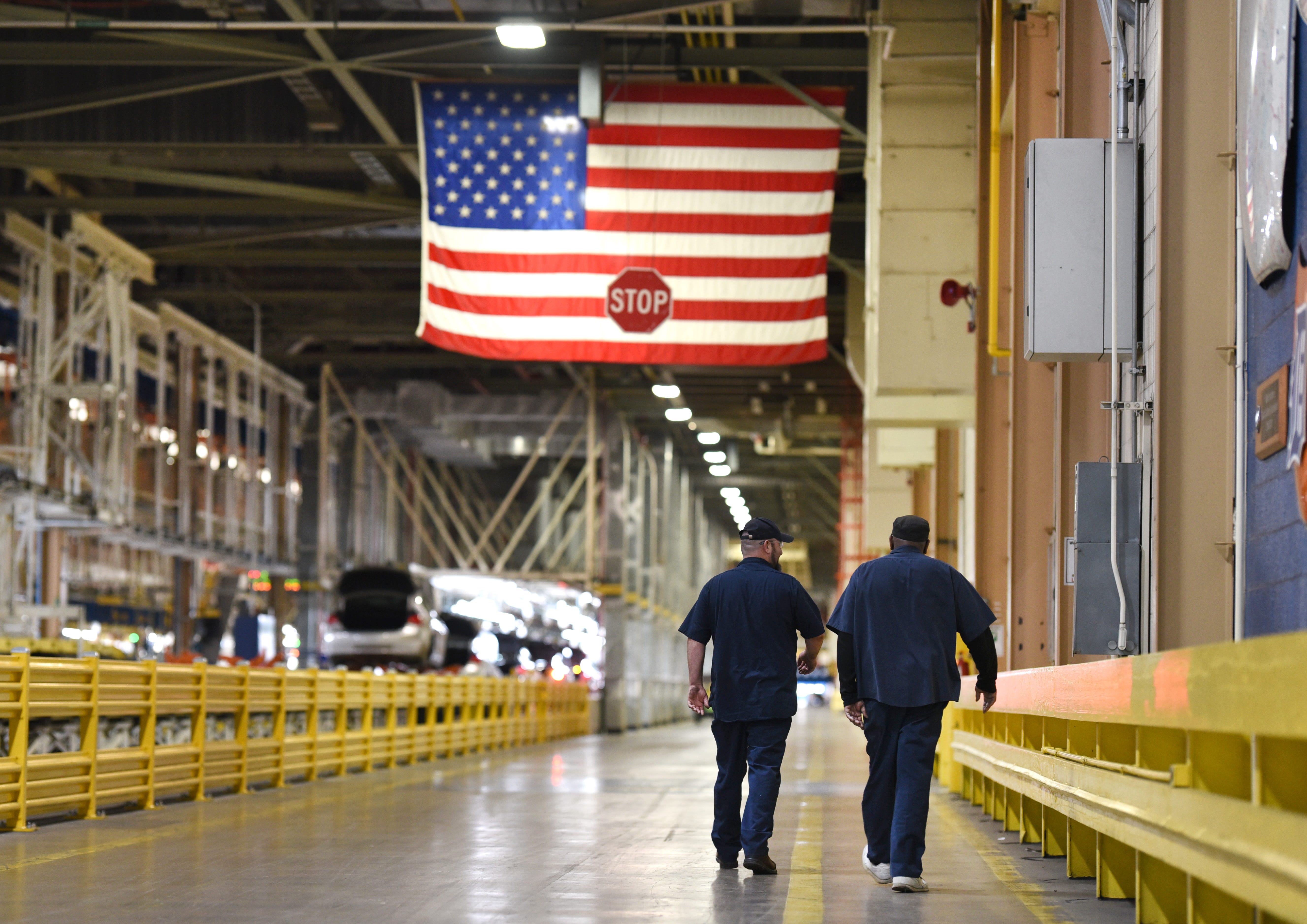 General Motors Detroit-Hamtramck plant employees walk towards the general assembly line as the American flag is seen overhead on Wednesday, February 12, 2020.