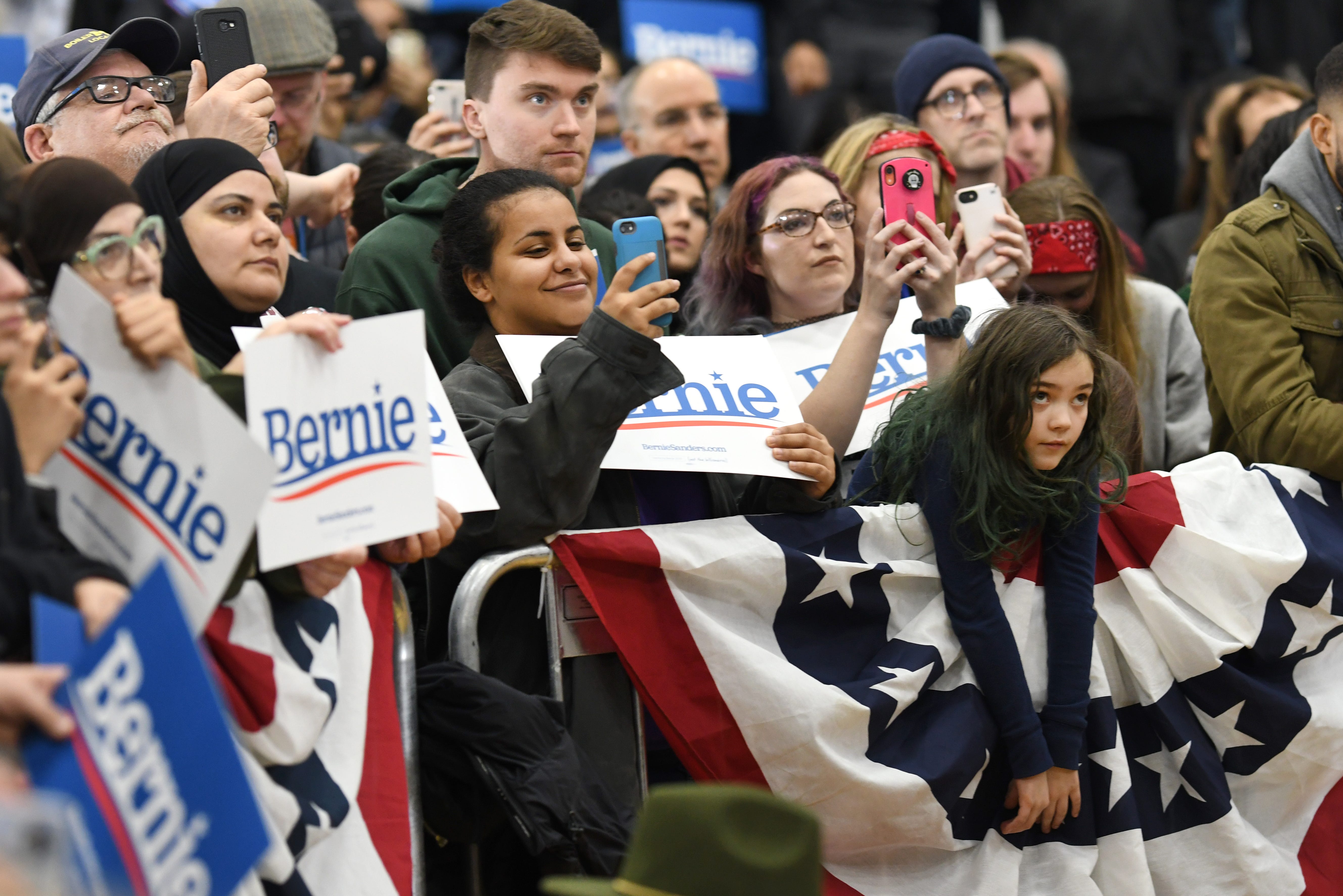 Supporters of presidential candidate Bernie Sanders listen and take photographs during the rally.