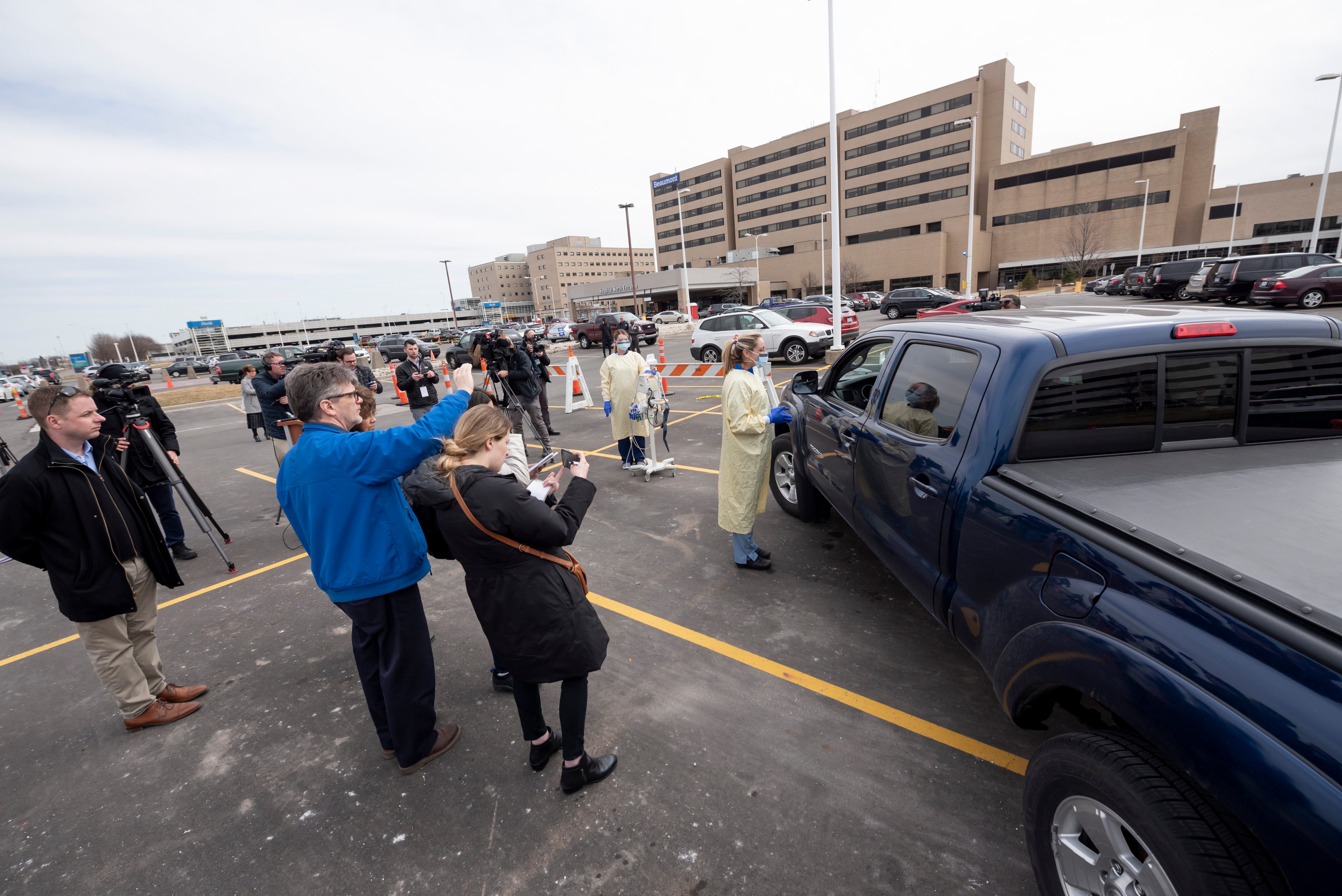 Members of the media record a demonstration of the drive-up screening process for the coronavirus at Beaumont hospital in Royal Oak, March 16, 2020. People concerned that they may be infected with the coronavirus are able to get screening done from their vehicles without entering the hospital.