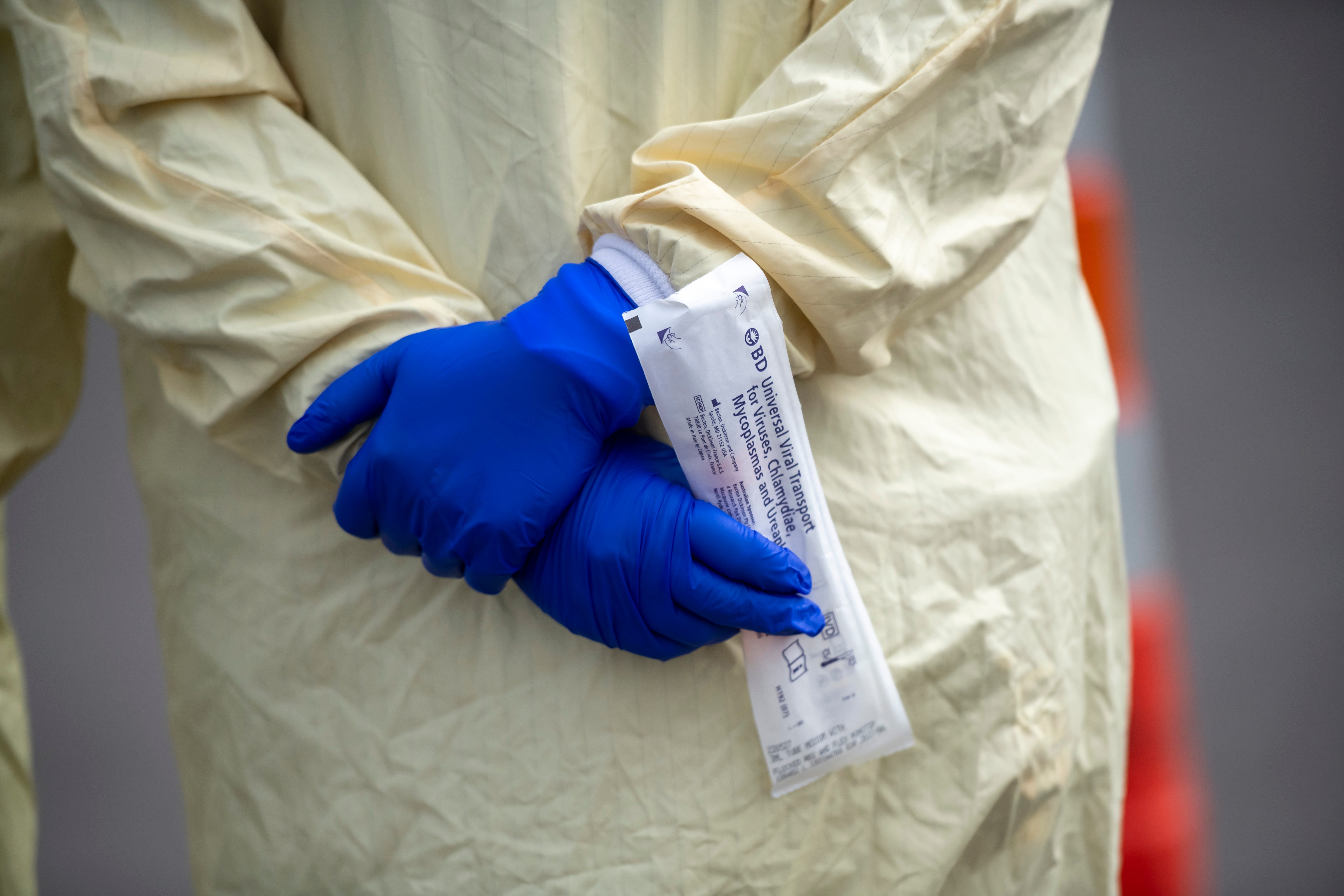Registered nurse Amena Beslic, director of the emergency center at Beaumont hospital in Royal Oak, holds a screening kit for a variety of viruses, including the coronavirus, March 16, 2020. Members of the public concerned that they may be infected with the coronavirus were able to get screening done from their vehicles at the hospital.