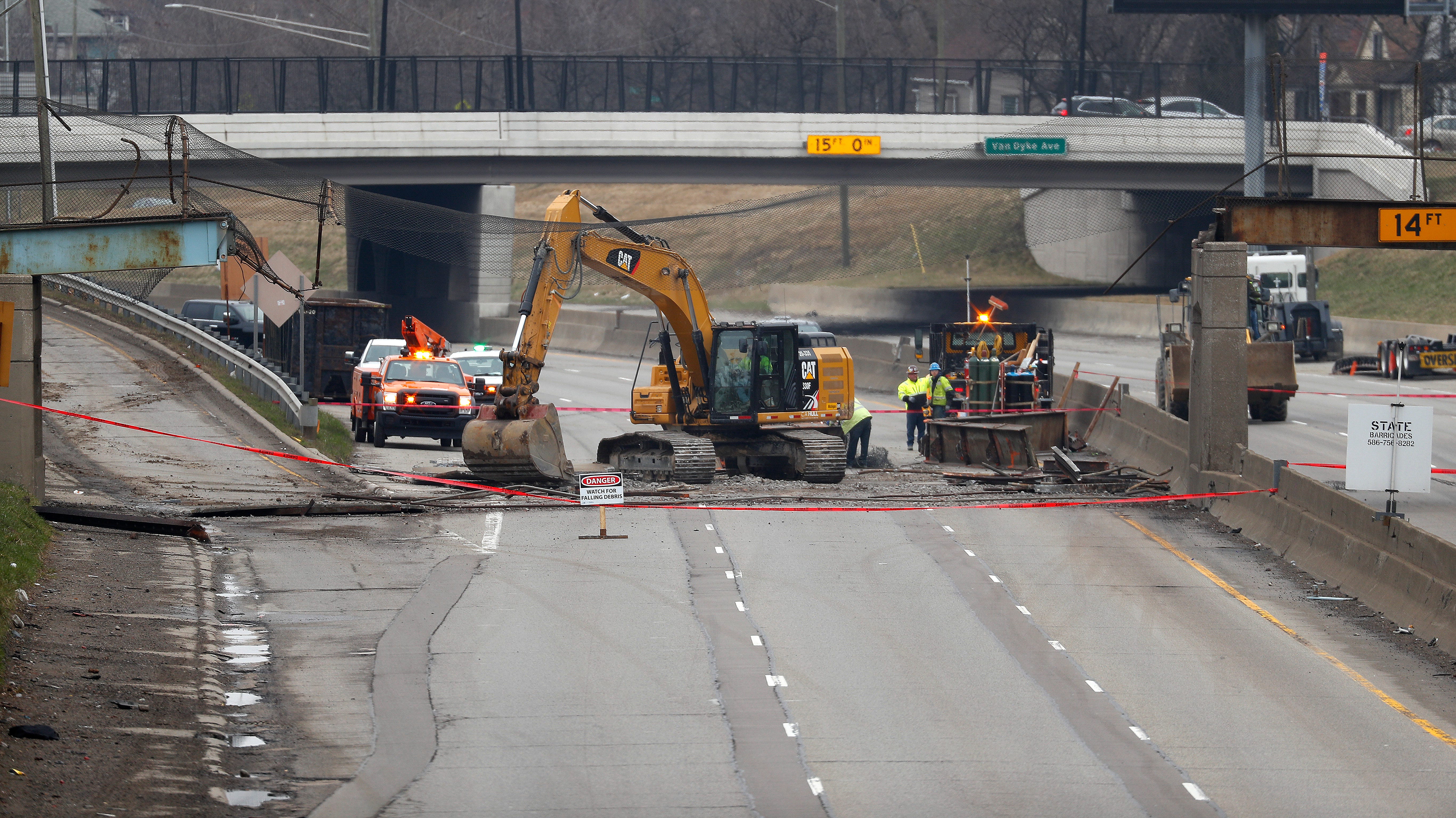 Workers clean debris from a collapsed pedestrian bridge on westbound Interstate 94 near Van Dyke Avenue Friday, March 27, 2020 in Detroit.