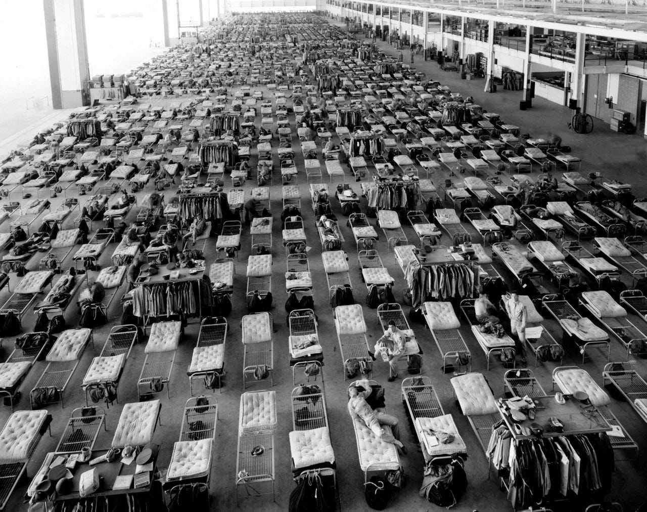 A hangar at Willow Run was turned into a barracks for Army personnel brought in to fly out the newly built bombers. Off-duty soldiers can be seen sprawled on some of the 1,300 cots.