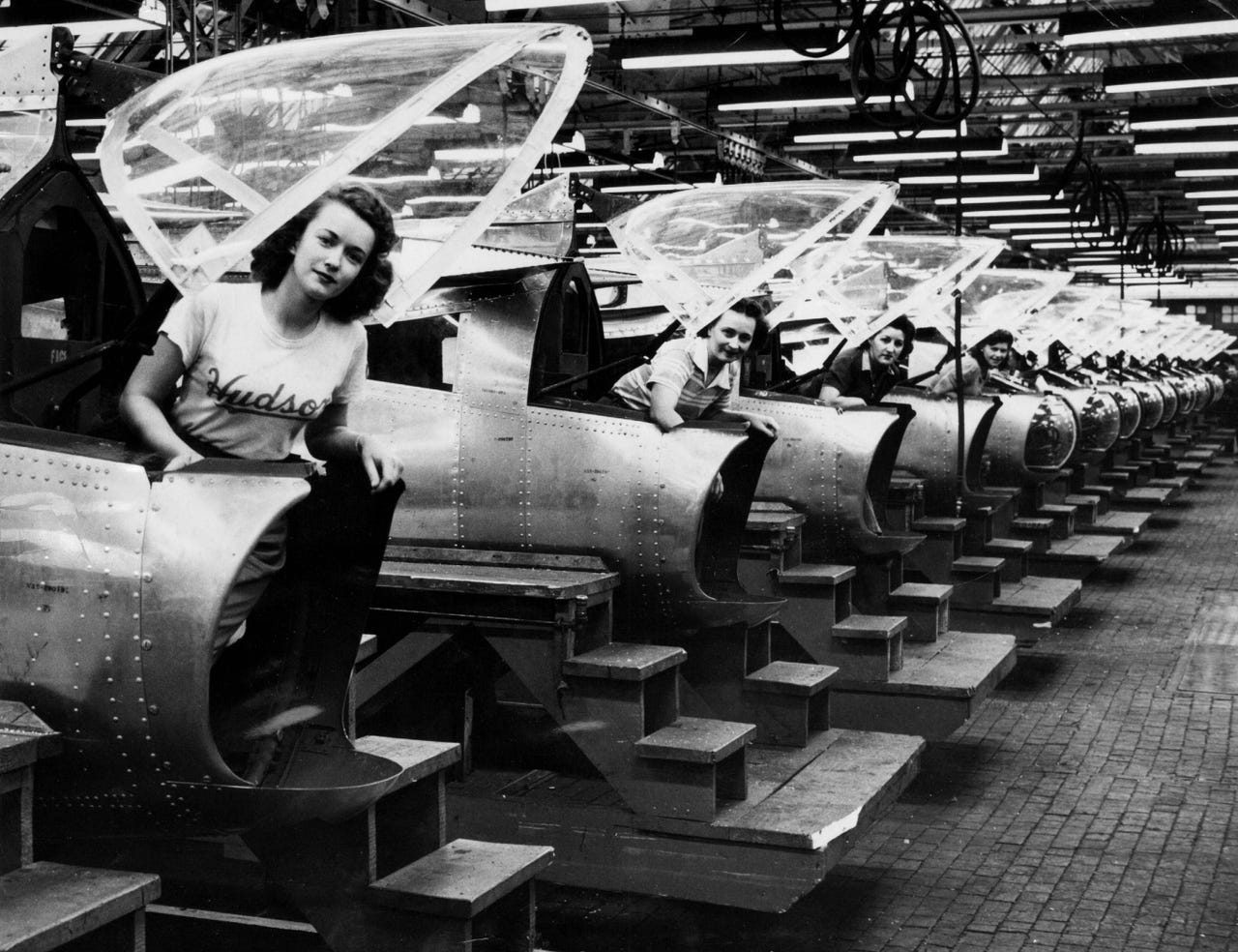 Four women stand beneath the Plexiglas bonnets in the tail of the Martin B-26 Marauder bomber fuselage sections built in a Detroit plant of the Hudson Motor Car Company in December 1944.