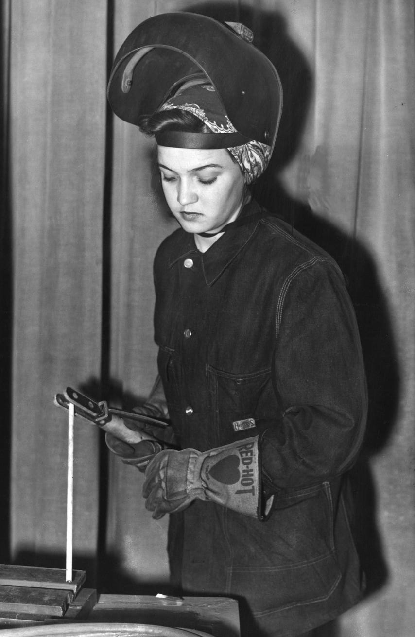 Annie Wells, dressed in clothes suitable for welding work, has her face shield ready to be pulled into position as she demonstrates the first stage of welding in an industrial clinic program to educate female students in general machine shop war work Dec. 17, 1942. Women entered the work force in huge numbers during the war.