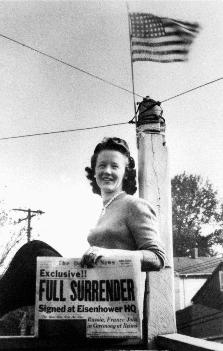 Stella Gleason holds a Detroit News paper with the headline "Exclusive!! Full Surrender" celebrating VE (Victory in Europe) day in May 1945. May 8, 1945 marked the surrender of Germany and an end to fighting in Europe; the war in the Pacific would continue until August.