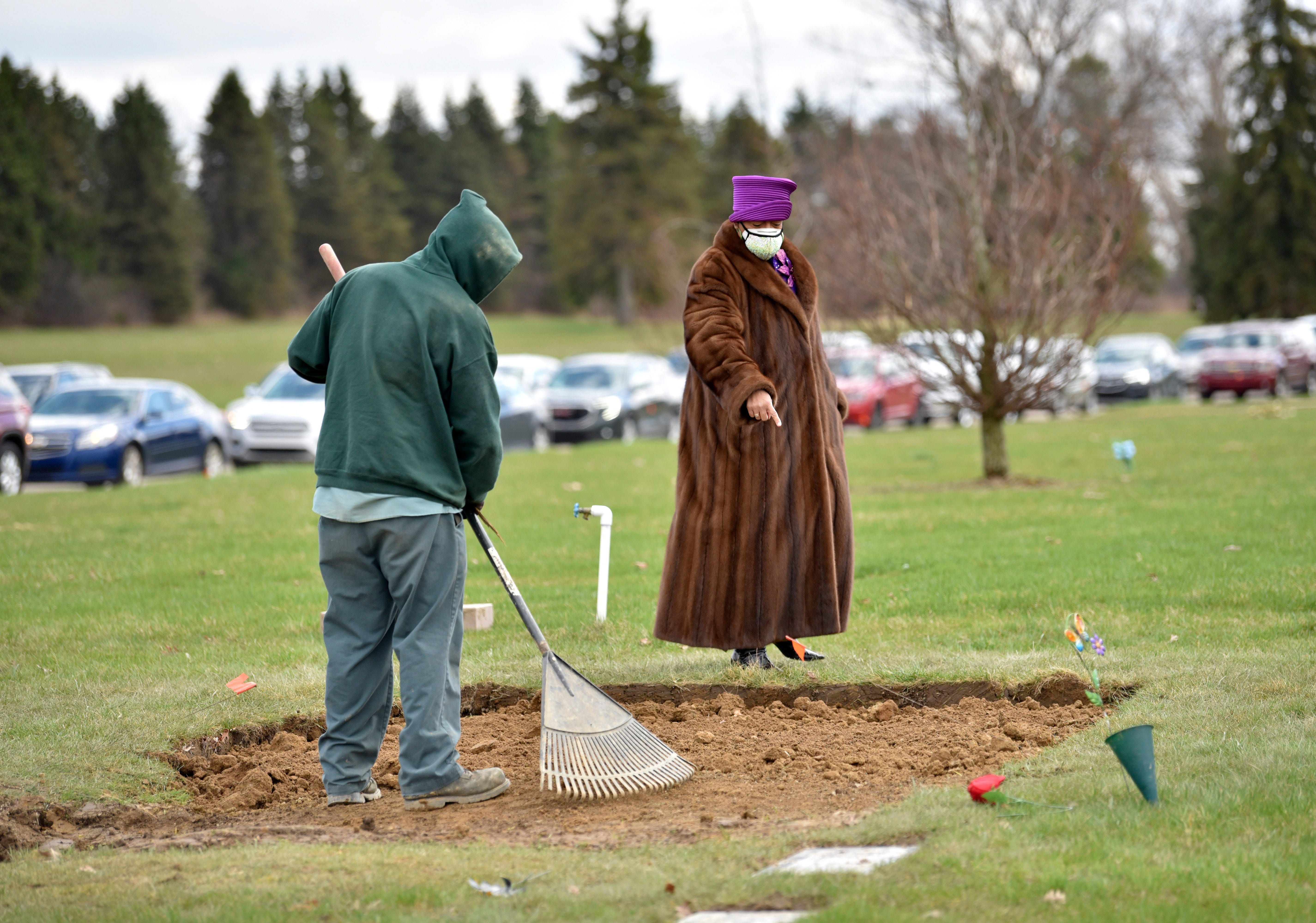 A Sunset Hills River Rest Cemetery grounds keeper rakes the gravesite of Freddie Lee Brown III and his father Freddie Lee Brown Jr. as mother/wife Sandy Brown arrives. Nobody was allowed at the gravesite until both casket vaults were covered with dirt to help prevent further spread of COVID-19.