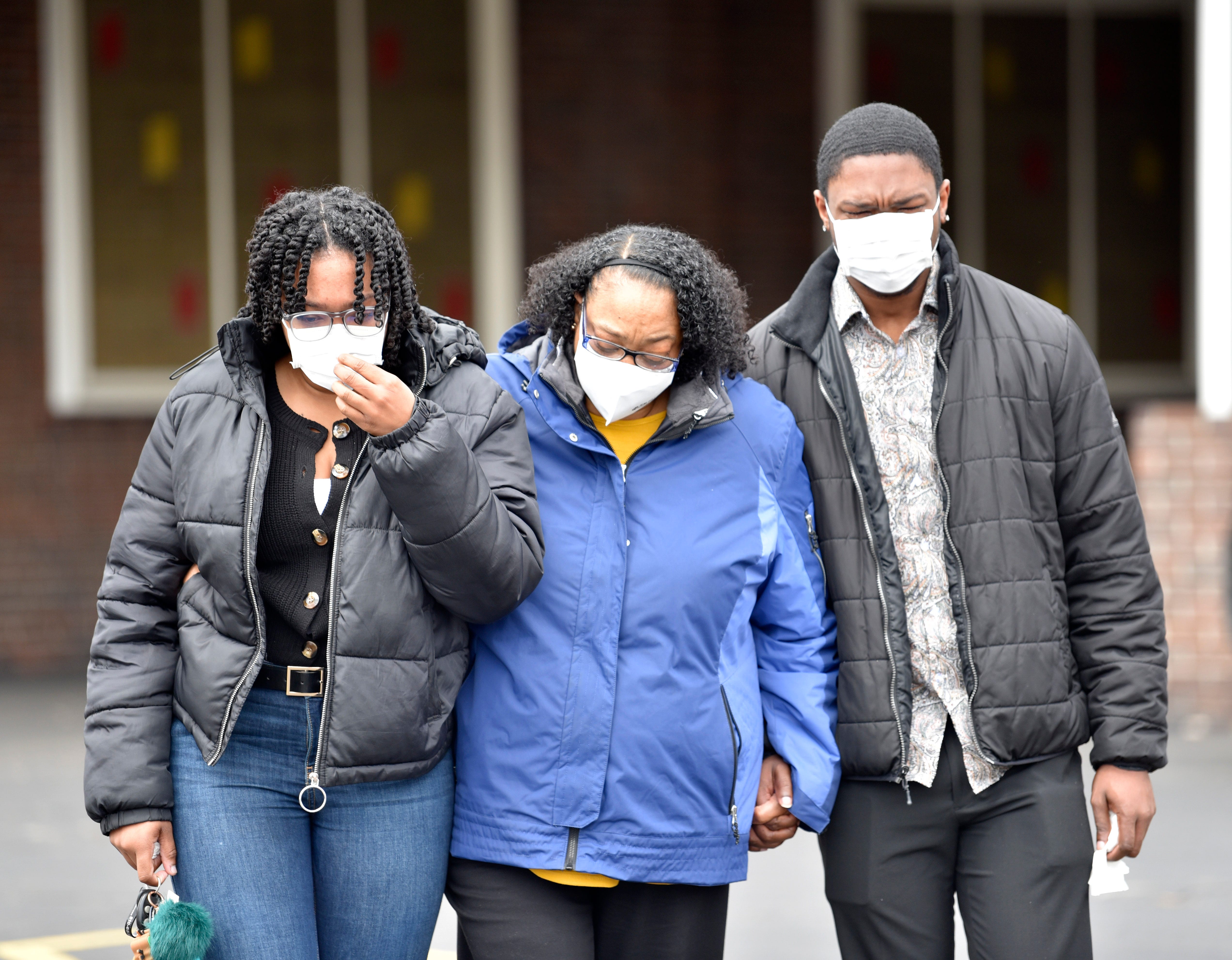 Tonya Brown, center, and her children, Rochelle Pompey, and Ronnie Pompey, Jr., all of Flint, cry as they leave the funeral home. Brown is sister to Brown Jr. and aunt to Brown III.