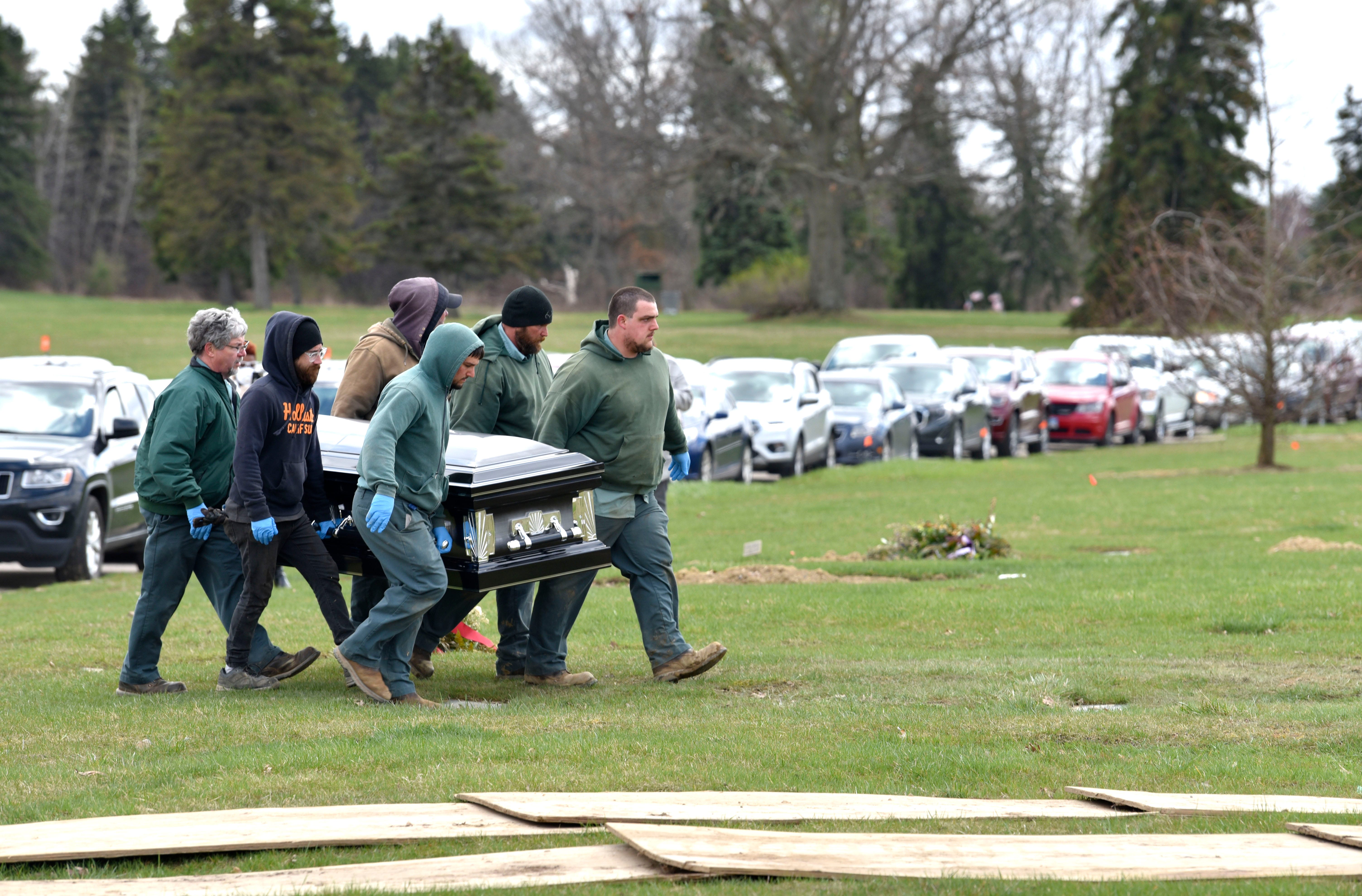 Sunset Hills River Rest Cemetery grounds keepers carry the casket of Freddie Lee Brown Jr. to his grave as family members and loved ones watch from their vehicles to adhere to social distancing guidelines to prevent further spread of COVID-19.