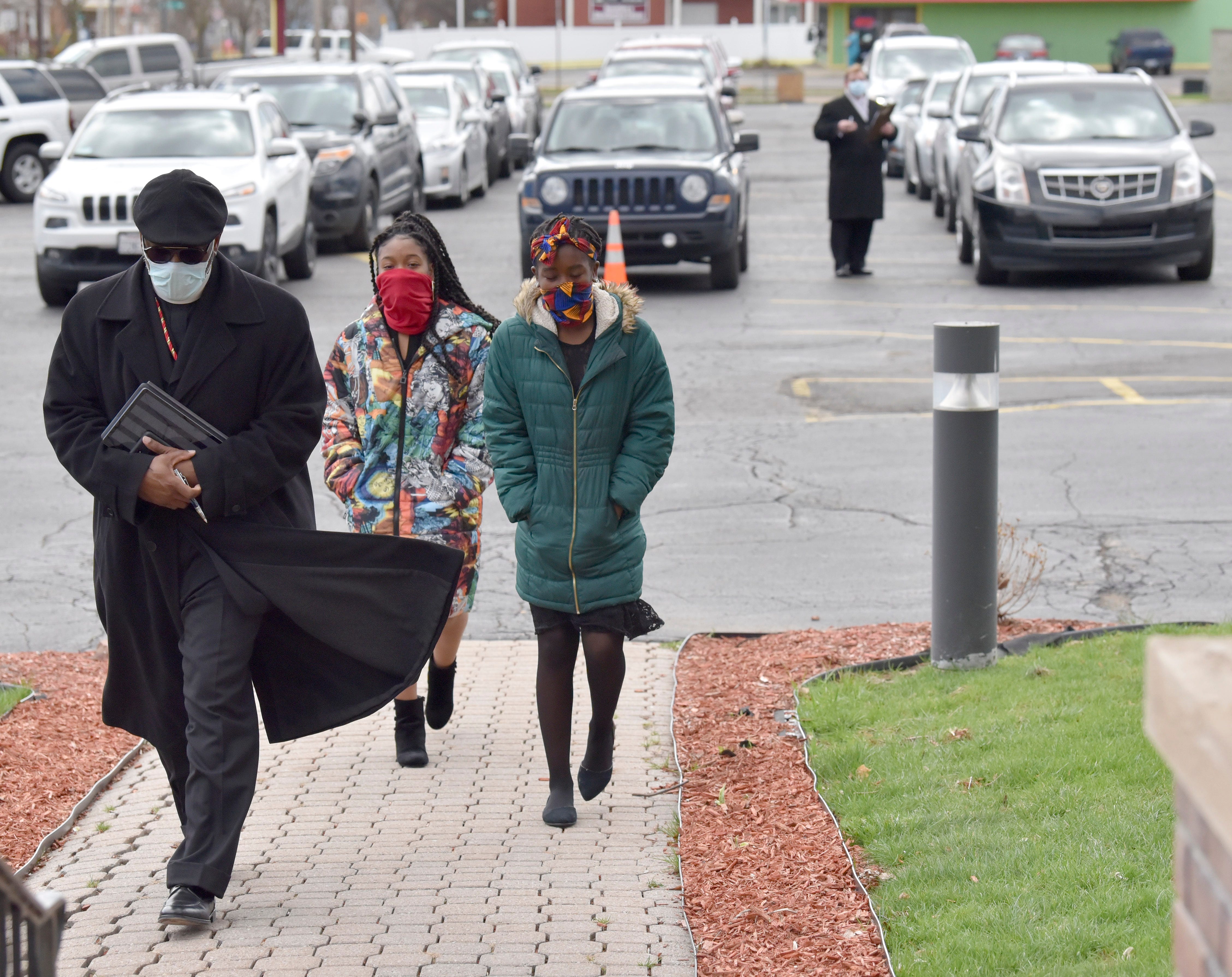 Jackson Memorial Temple Church of God in Christ Pastor Kiemba Knowlin, and his daughters, Nehderi Knowlin, 16, center, and Zhenya Knowlin, 12, all of New Baltimore, enter the funeral home to pay their respects as other invited guests wait in their cars for their turn, on Firday, April 10, 2020.