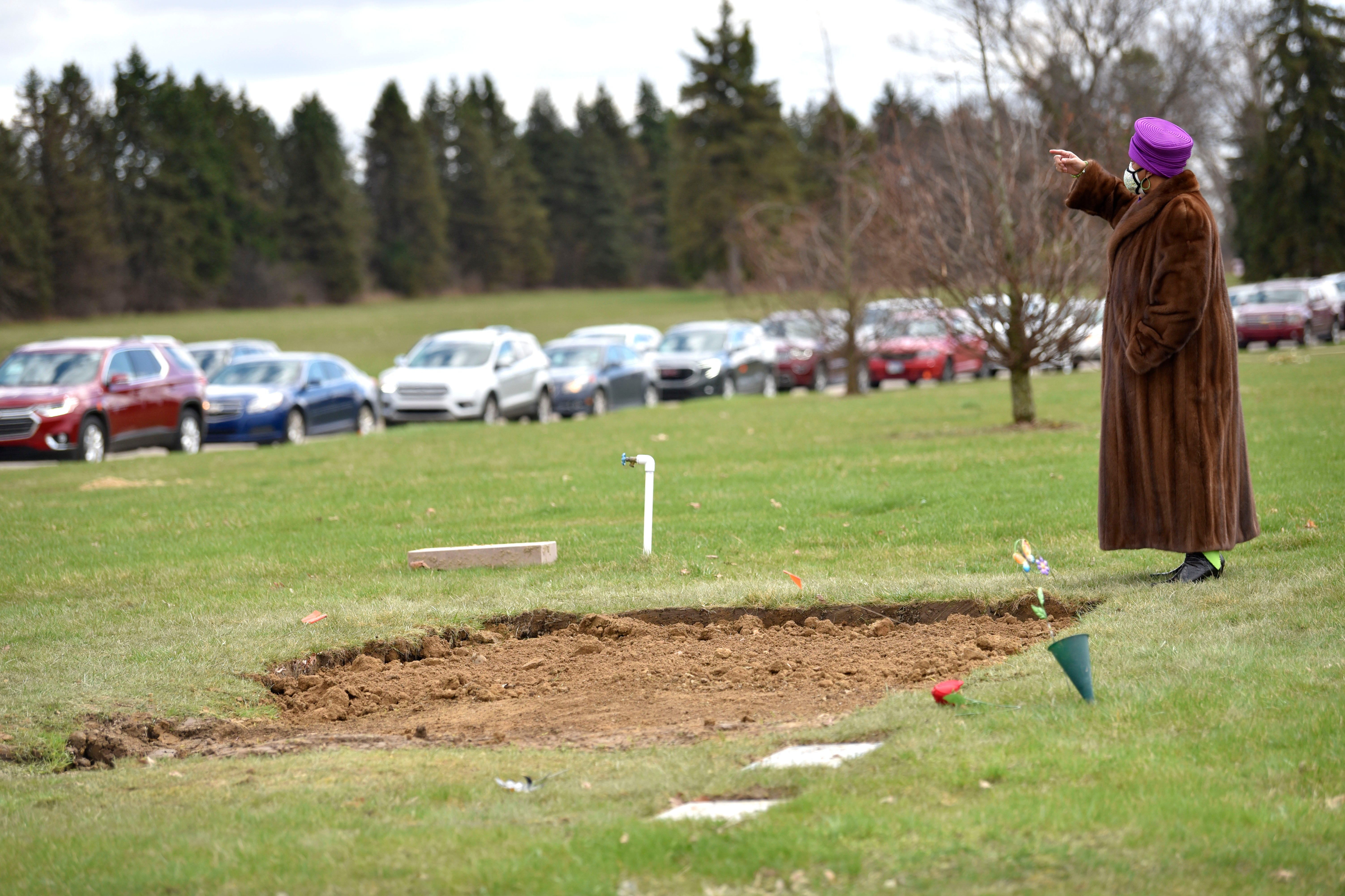 Sandy Brown waves over close friends and family members to the gravesite as others pay respects from their vehicles.