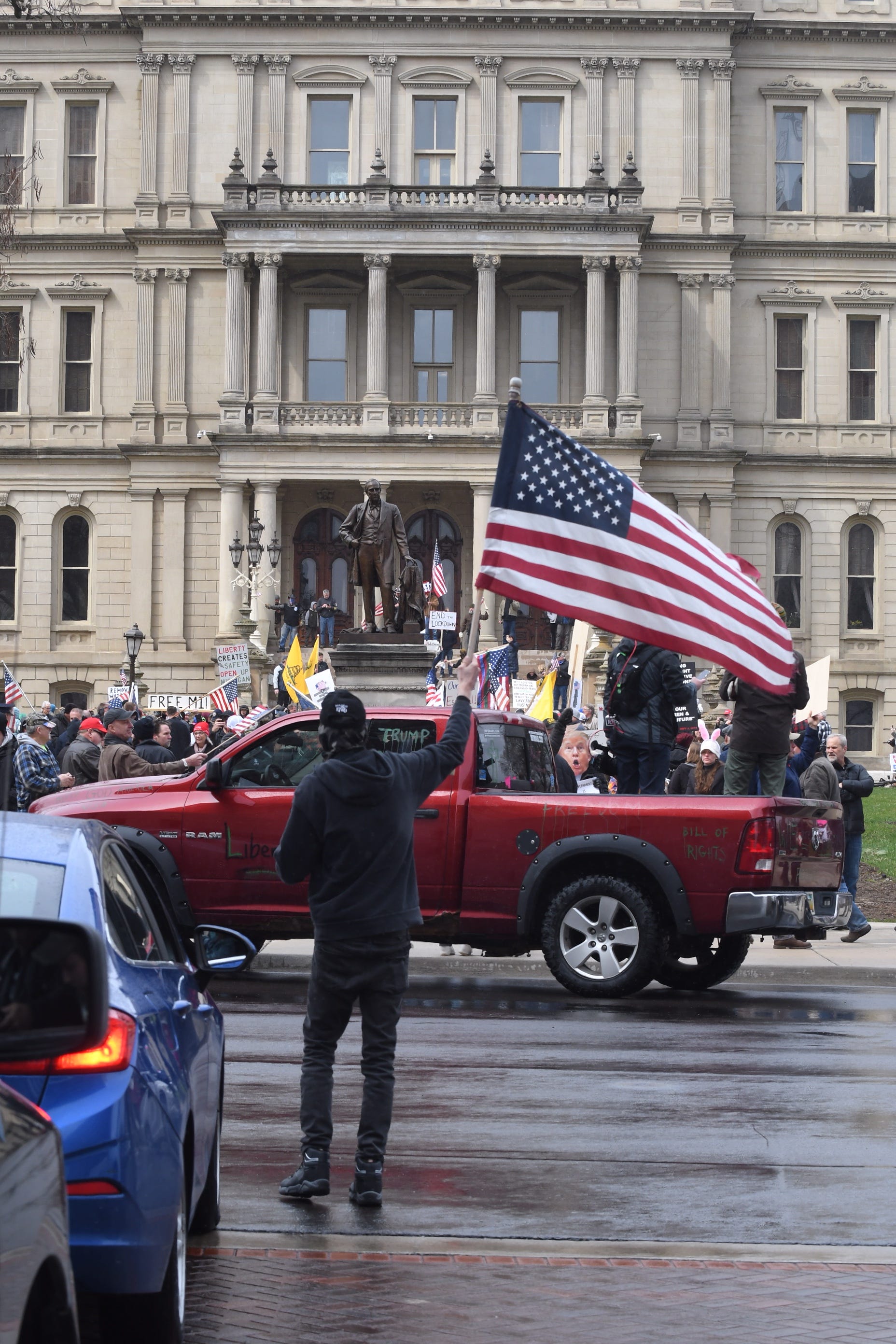 Individuals leave their vehicles to gather on the front steps of the state Capitol building to protest Gov. Gretchen Whitmer ' s stay-home order.