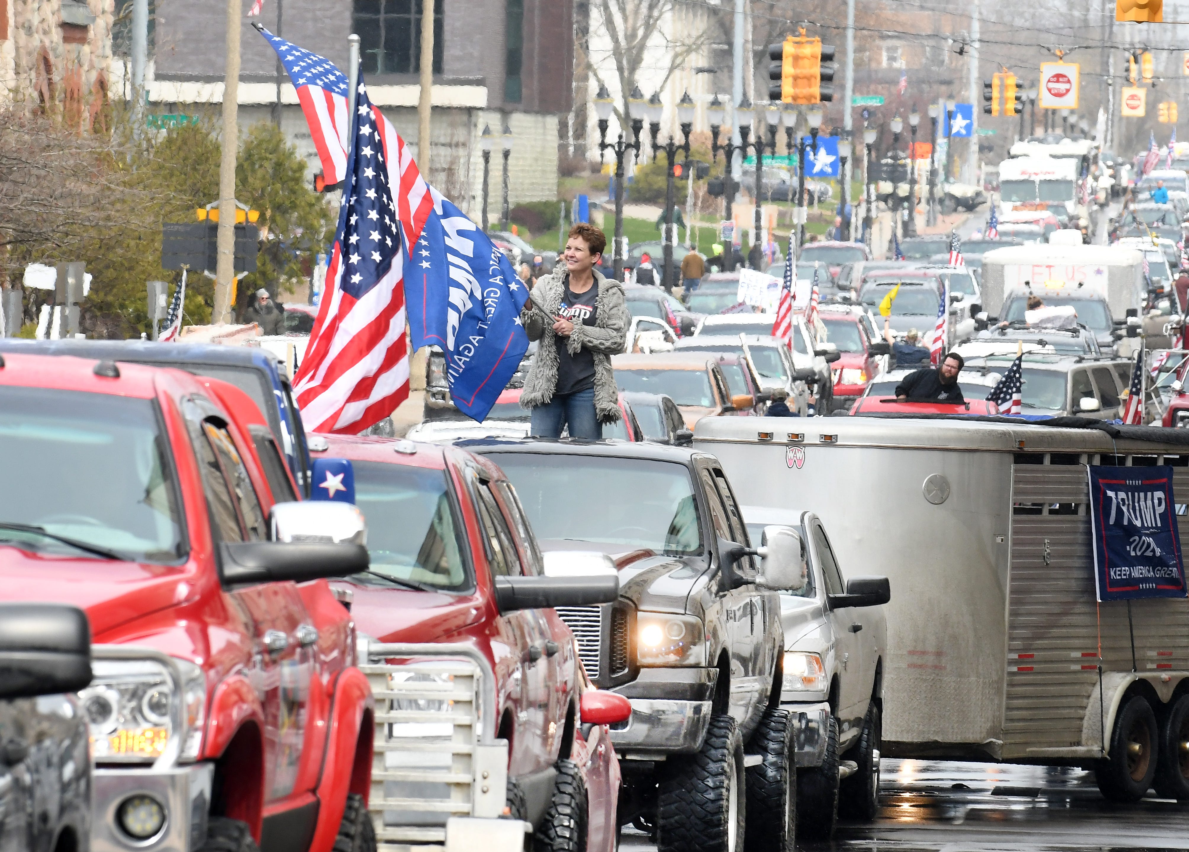Deborah Creque waves American and Donald Trump flags as she and other protesters surround the state Capitol during Operation Gridlock in Lansing on April 15, 2020.