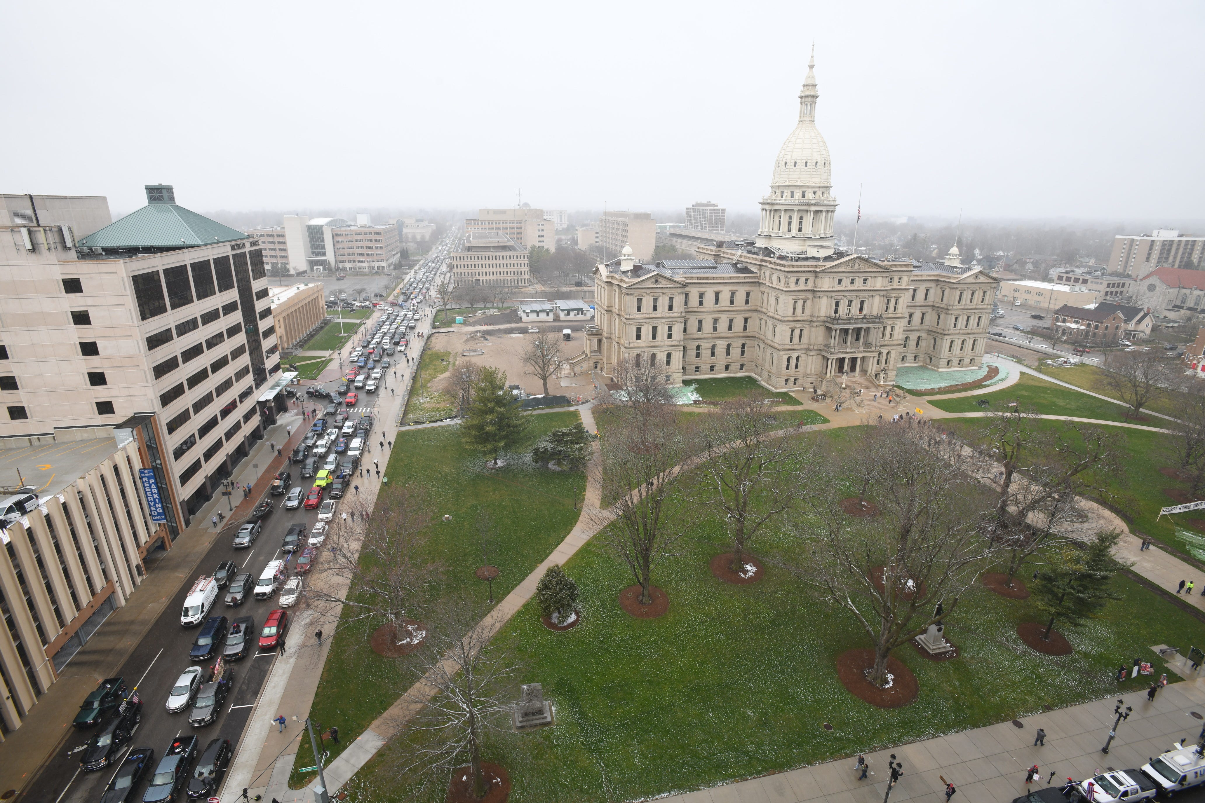 Hundreds of vehicles driven by individuals protesting Gov. Gretchen Whitmer ' s stay-home order jam the streets near the state Capitol building in Lansing, honking their horns and raising a ruckus before the official protest is even set to begin at noon on Wednesday, April 15, 2020.