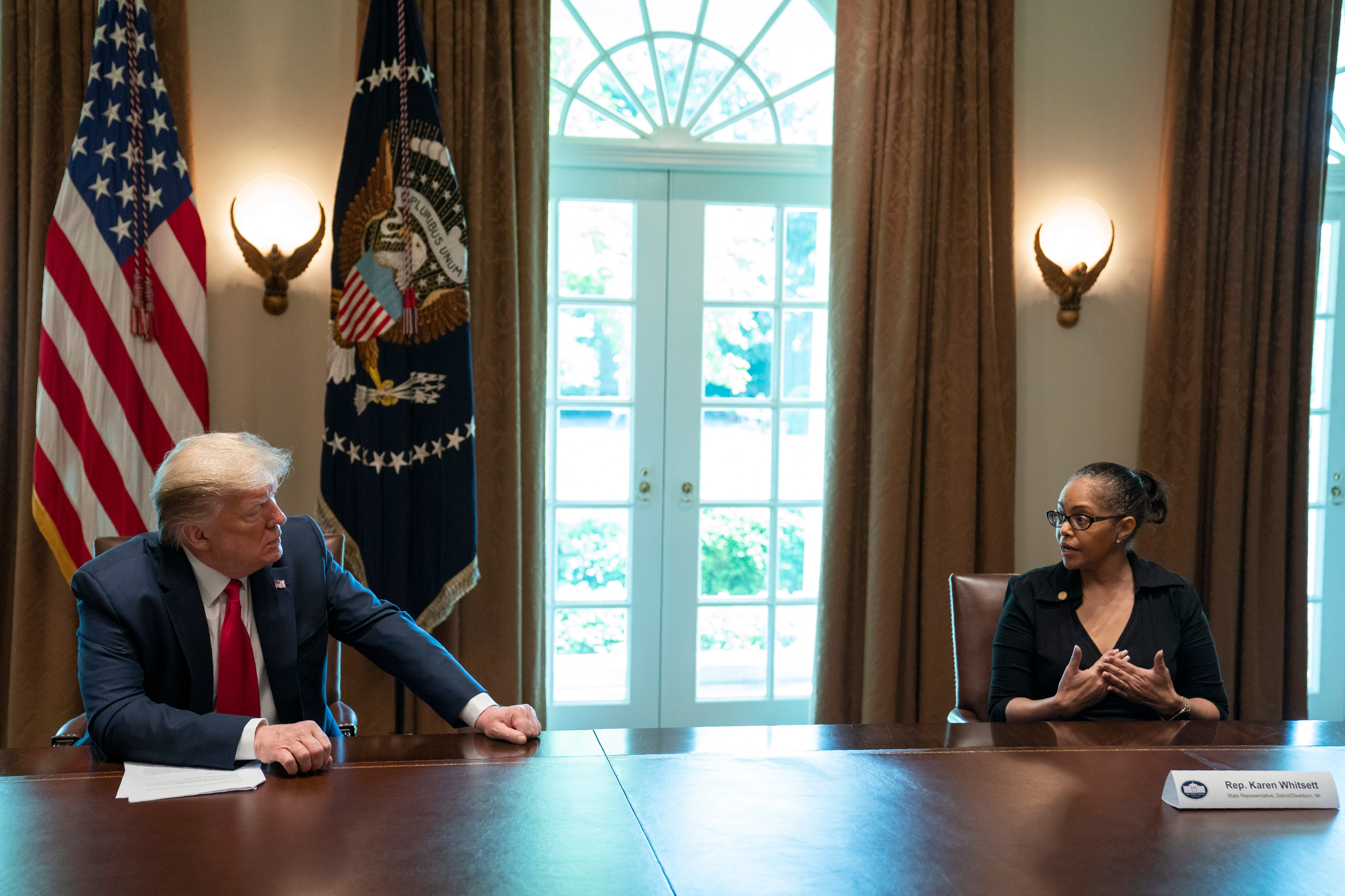 President Donald Trump listens as Karen Whitsett shares her story of recovery from COVID-19, in the Cabinet Room of the White House, Tuesday, April 14, 2020, in Washington.
