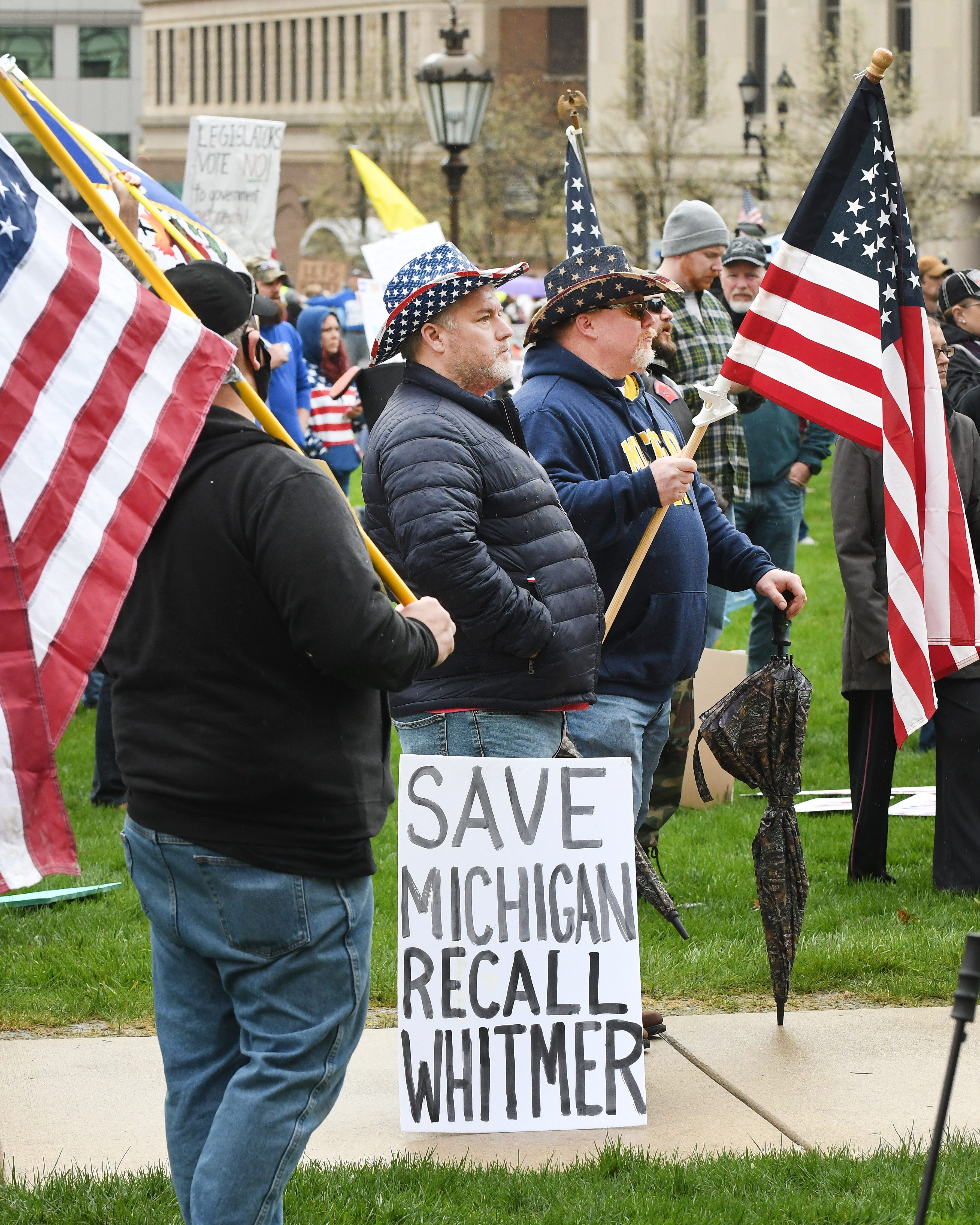 Calvin Hamilton and Chad Goetz listen to speakers during the " American Patriot Rally, " to protest Gov. Gretchen Whitmer ' s coronavirus policies, outside the Michigan Capitol in Lansing on April 30, 2020.