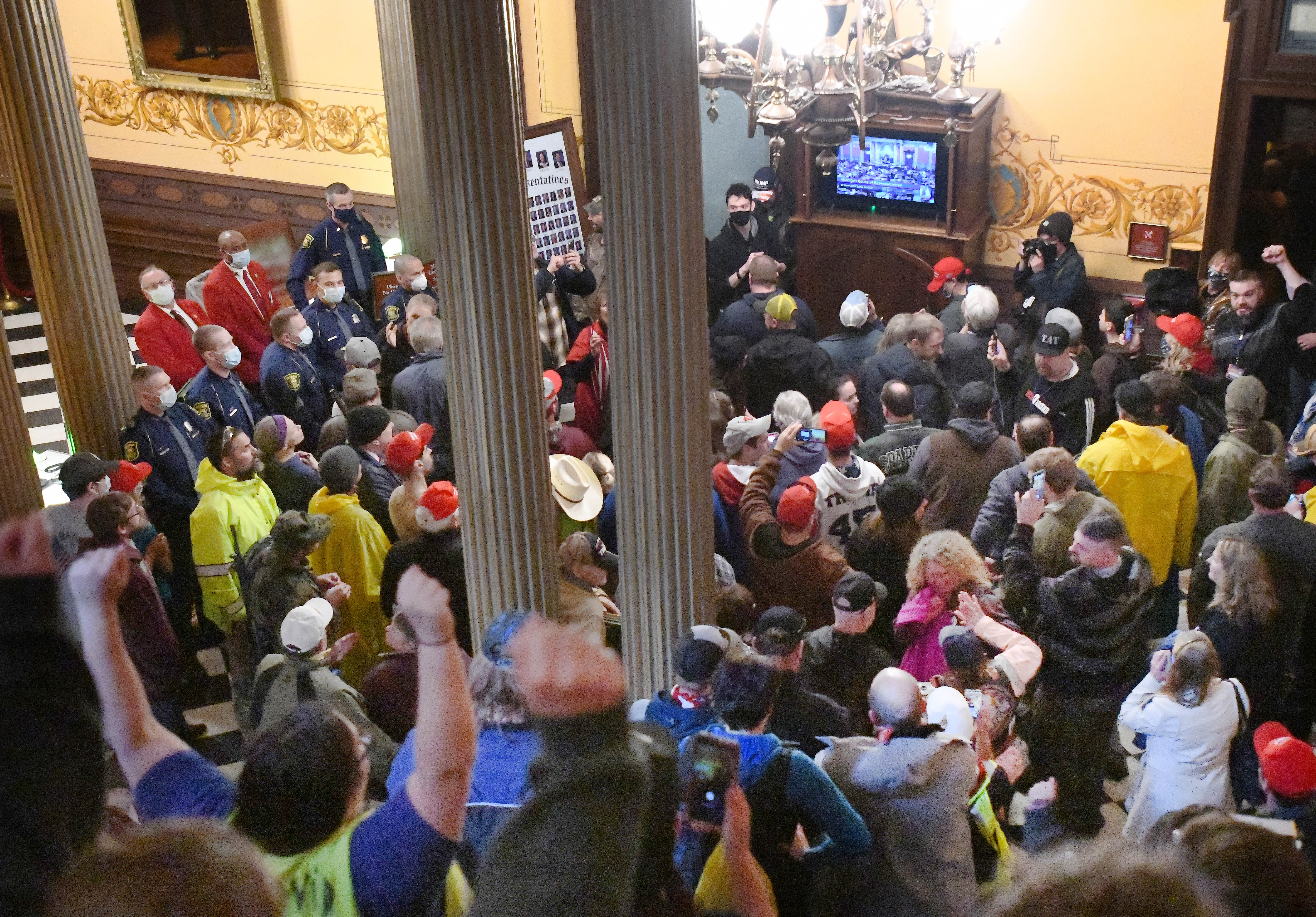 Protesters cheer as they watch the proceedings on a monitor outside the House of Representatives inside the Capitol in Lansing, The Michigan House approved a resolution that authorizes Speaker Lee Chatfield, R-Levering, to file a legal challenge against unilateral efforts Gov. Gretchen Whitmer has taken to prevent the spread of COVID-19.