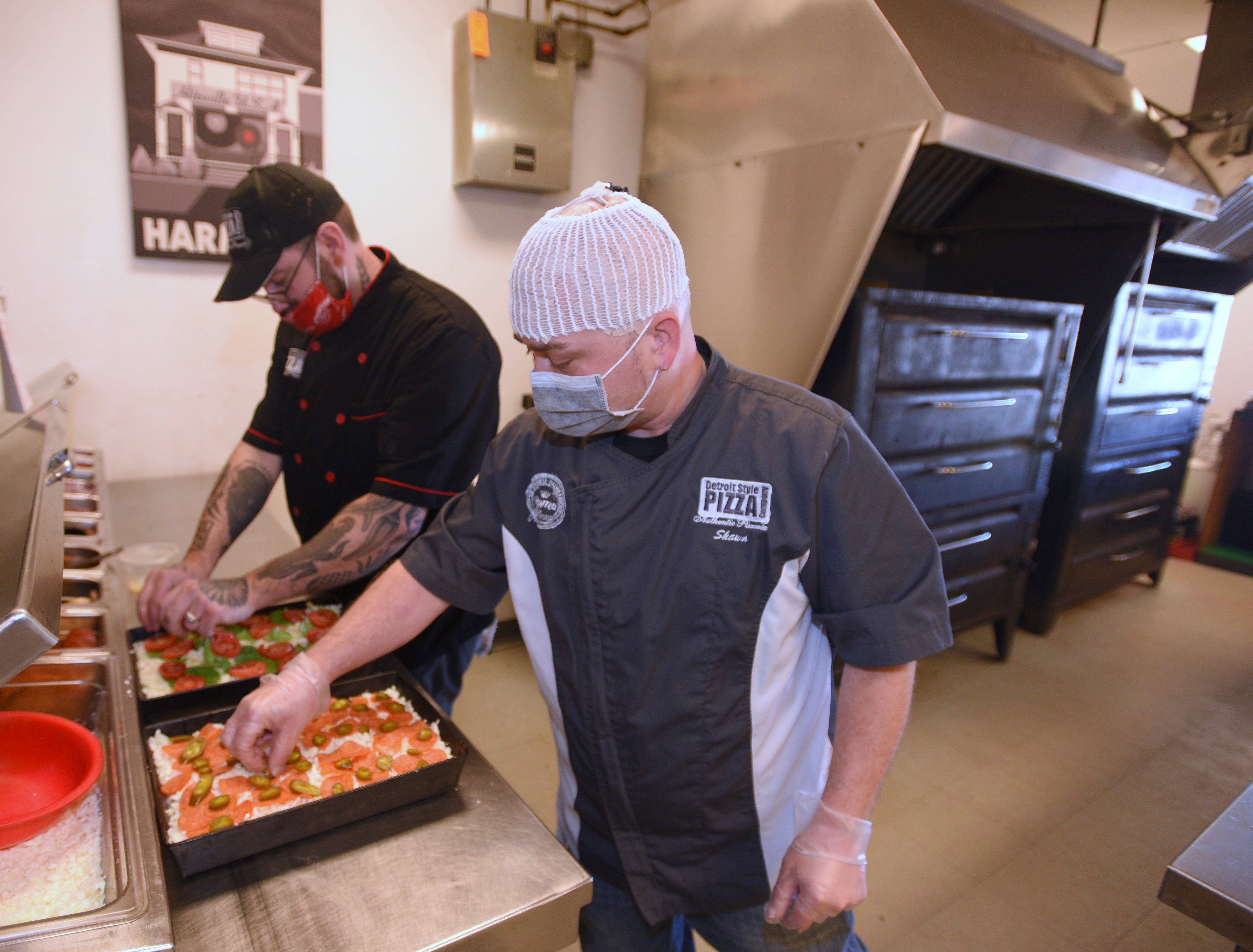 Co-owners / chef Joe Maino, left, of Ypsilanti, and award-winning pizza-maker Shawn Randazzo, of Macomb Twp., put ingredients on their Margherita In The D Pizza and Harper Hornet pizza, respectively, at their St. Clair Shores pizzarella, Wednesday.
