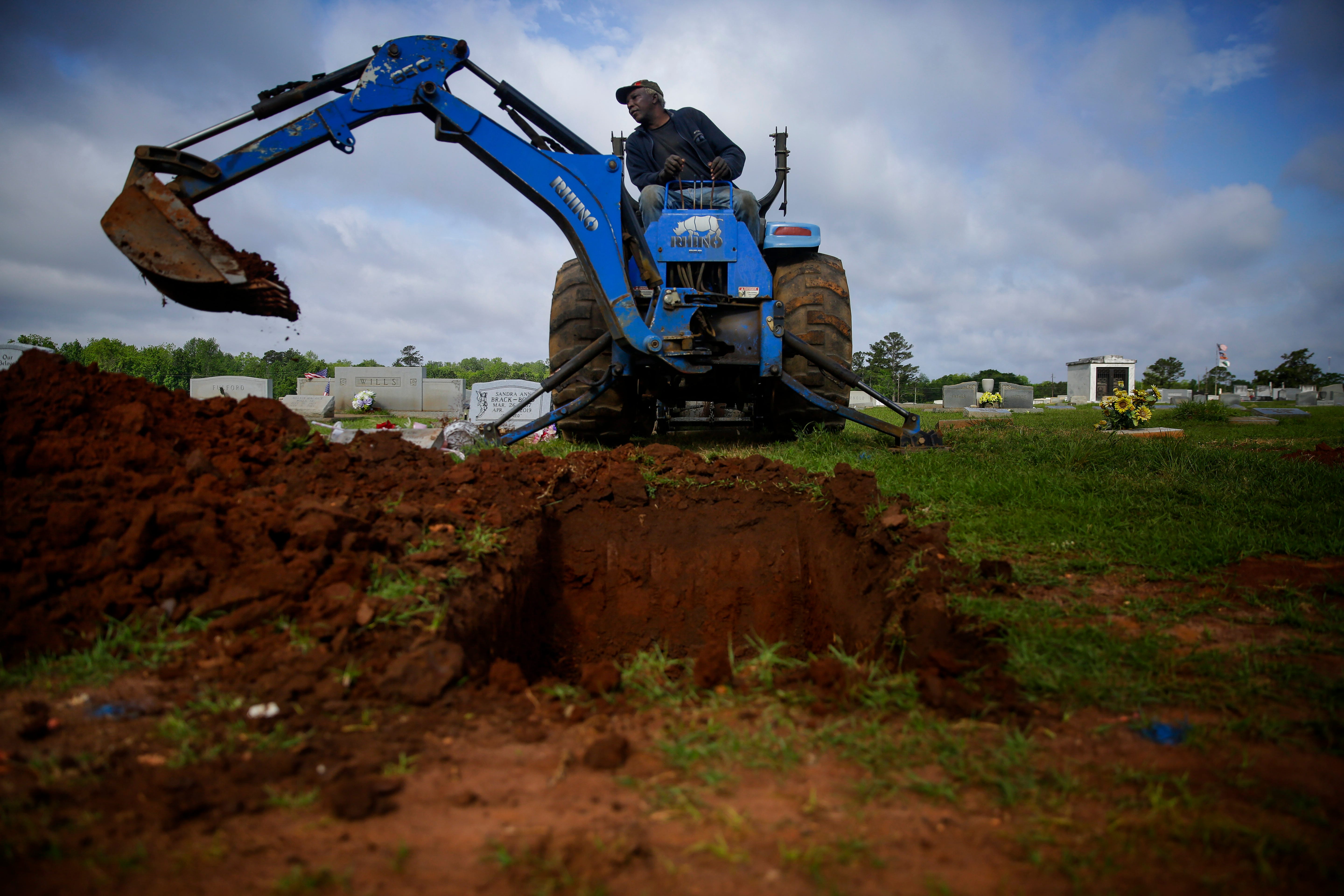 Horace Bell, 60, of Americus, Ga., uses an excavator to dig a grave at Cedar Hill Cemetery on Saturday, April 18, 2020, in Dawson, Ga.