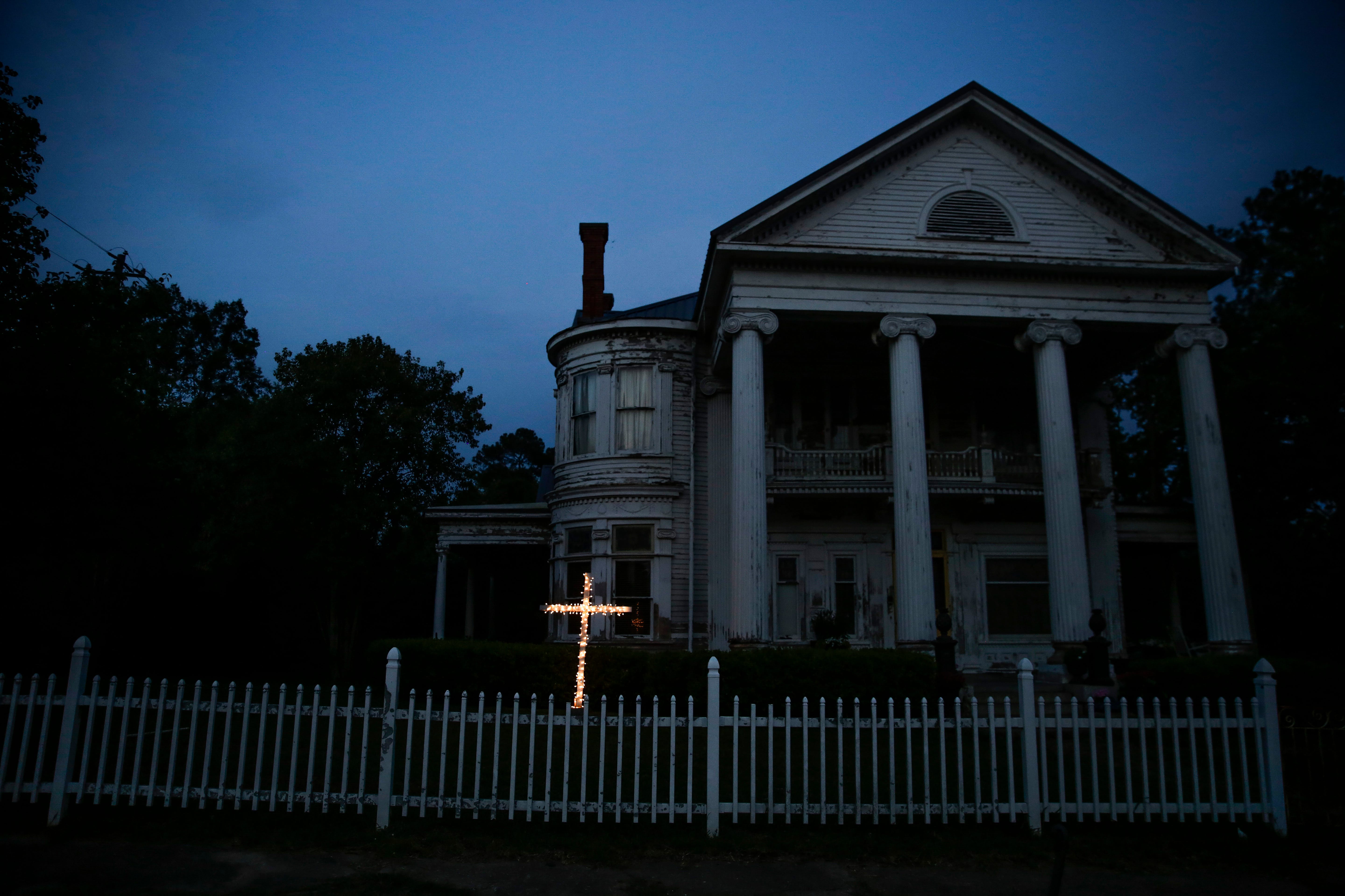 An illuminated cross stands in front of a residence near downtown Dawson, Ga., on Friday, April 17, 2020. Of the 20 counties with the highest death rate in America, six of them are in rural southwest Georgia, where there are no packed skyrise apartment buildings or subways.