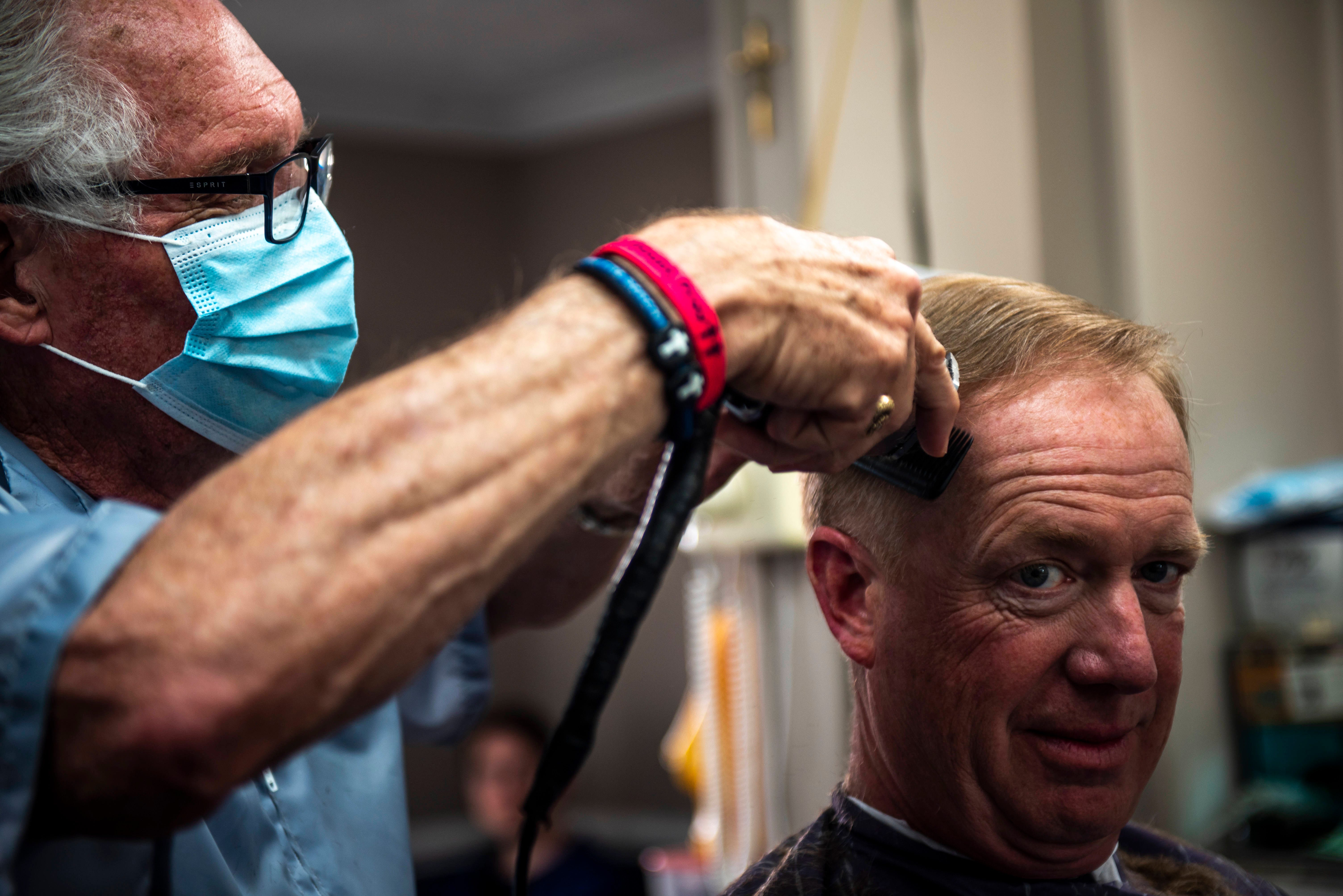 Karl Manke, 77, cuts the hair of Craig Wiker of Dowagiac at his barbershop in Owosso, on May 11, 2020.