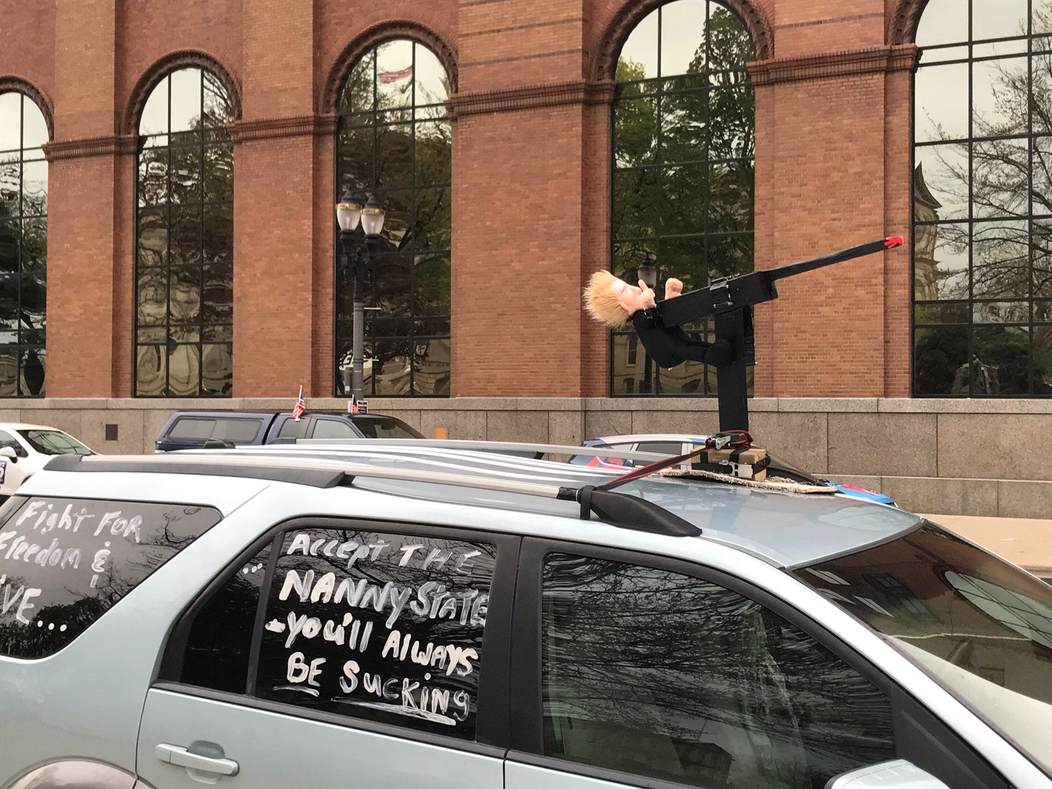 A fake machine gun is mounted atop a protester's car.