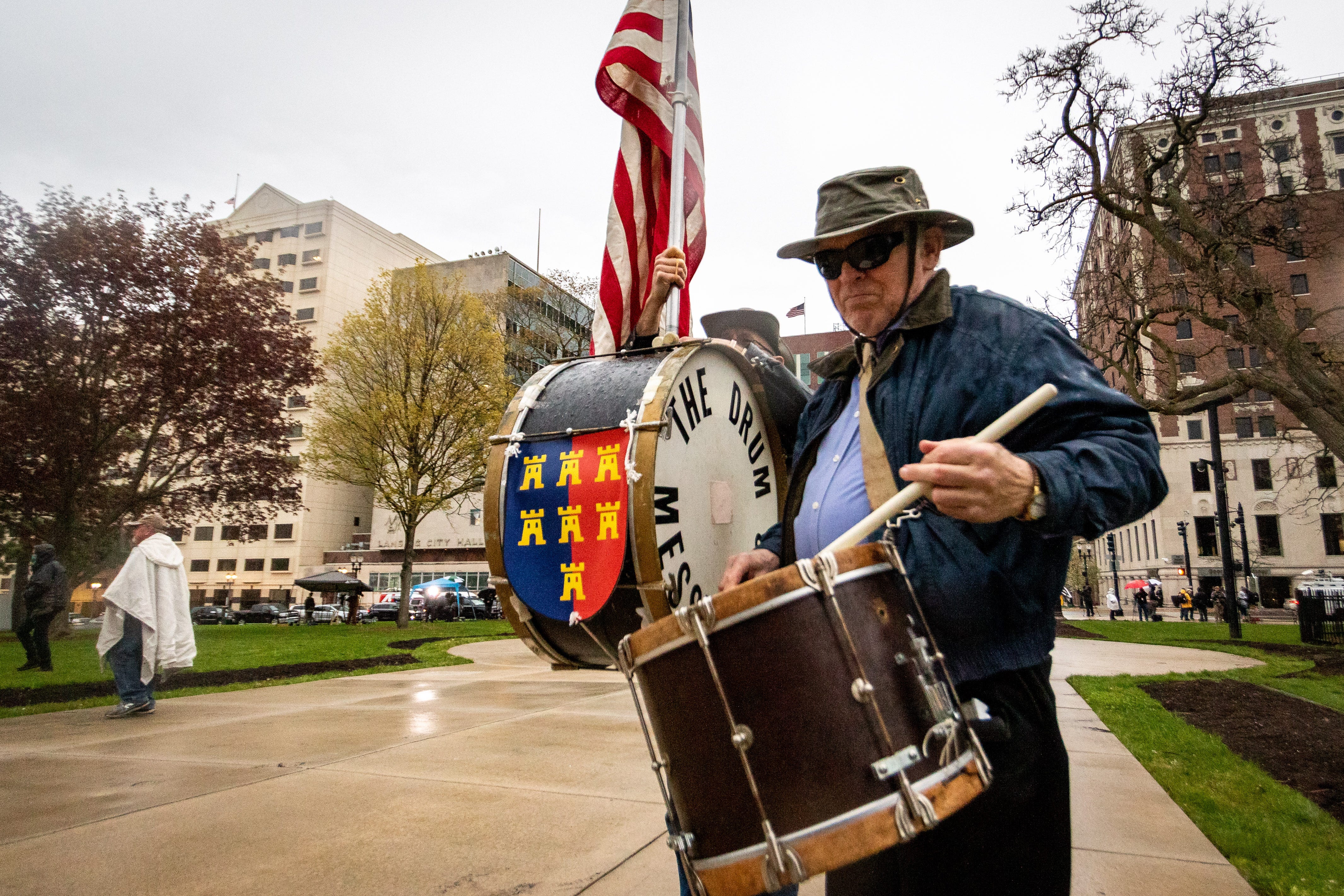 Rob Schneider, center, and Mike Renner, right, both of Royal Oak march in protest. Renner, born in Hungary, escaped from Europe during World War II.  The crest on the front of the drum is his family's crest from the Carpathian Saxons.