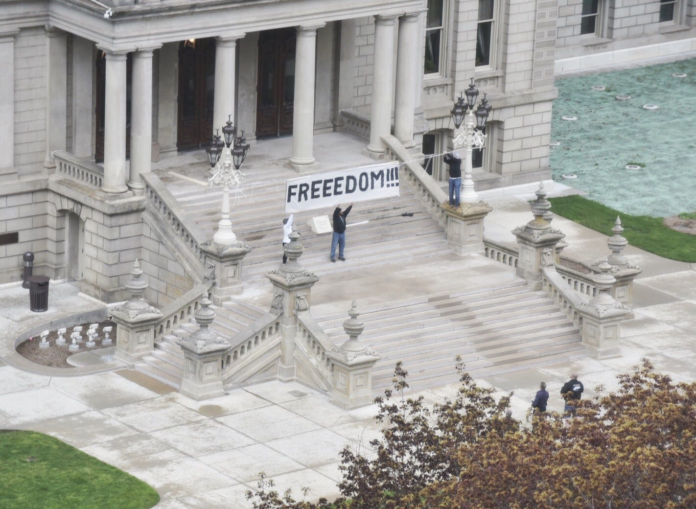 Protesters in Lansing get an early start on Thursday, May 14, 2020, demonstrations by hanging a sign above the Capitol stairs.
