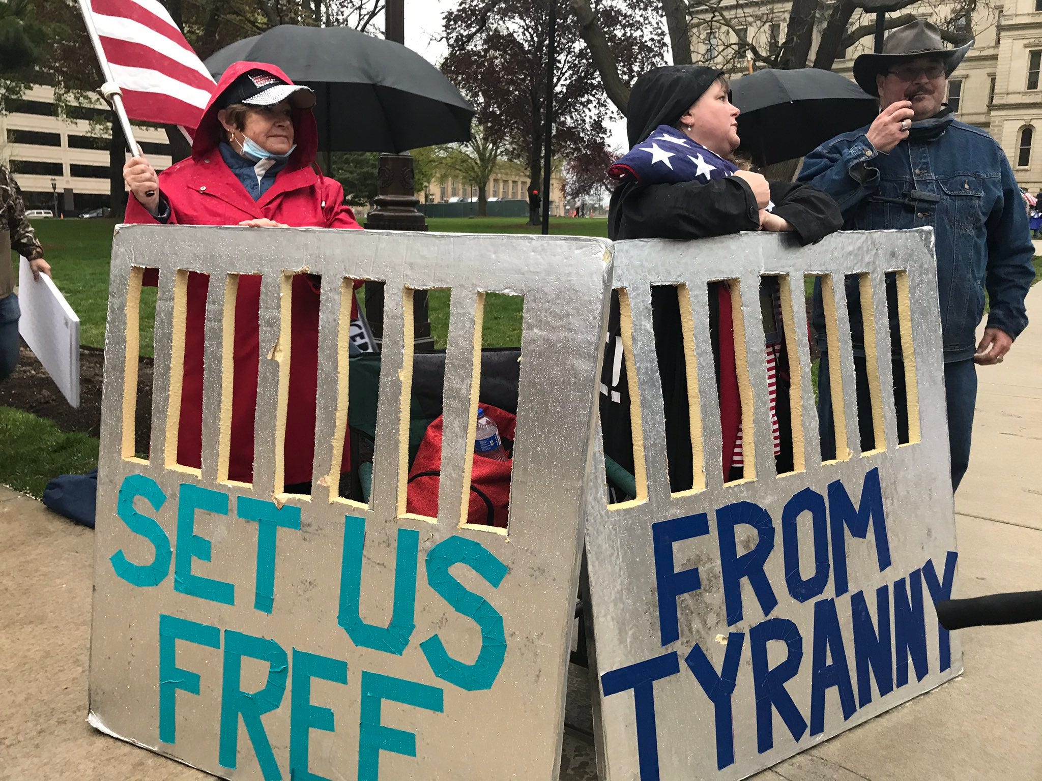 Protesters carry signs meant to look like prison bars at the Michigan Capitol.