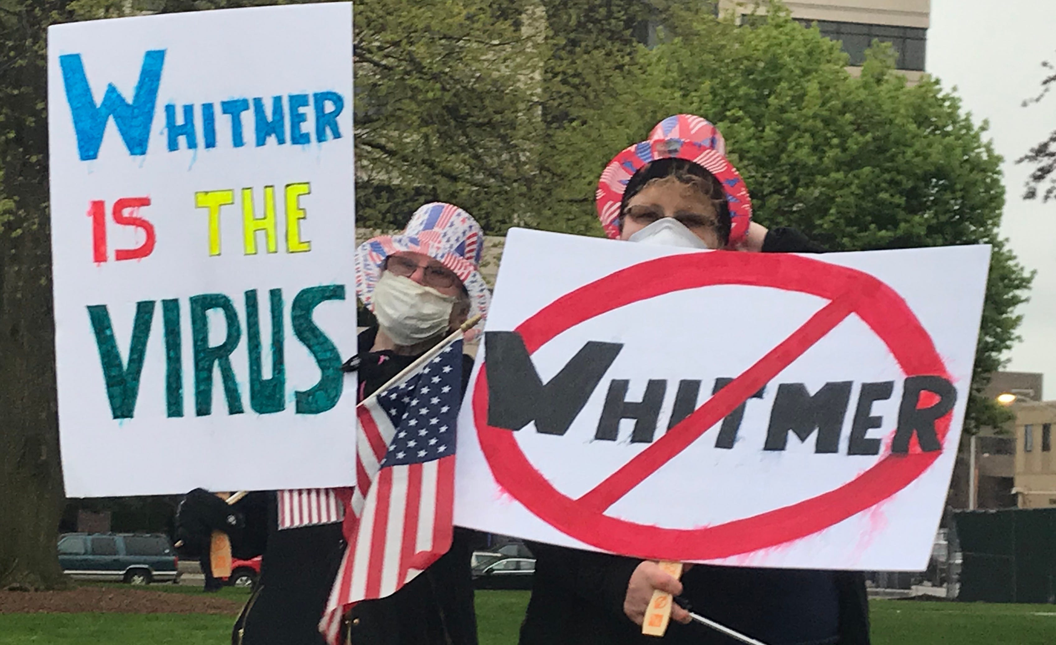 Two protesters pose for a photo outside the Michigan Capitol on Thursday, May 14, 2020, during a demonstration against COVID-19 restrictions.