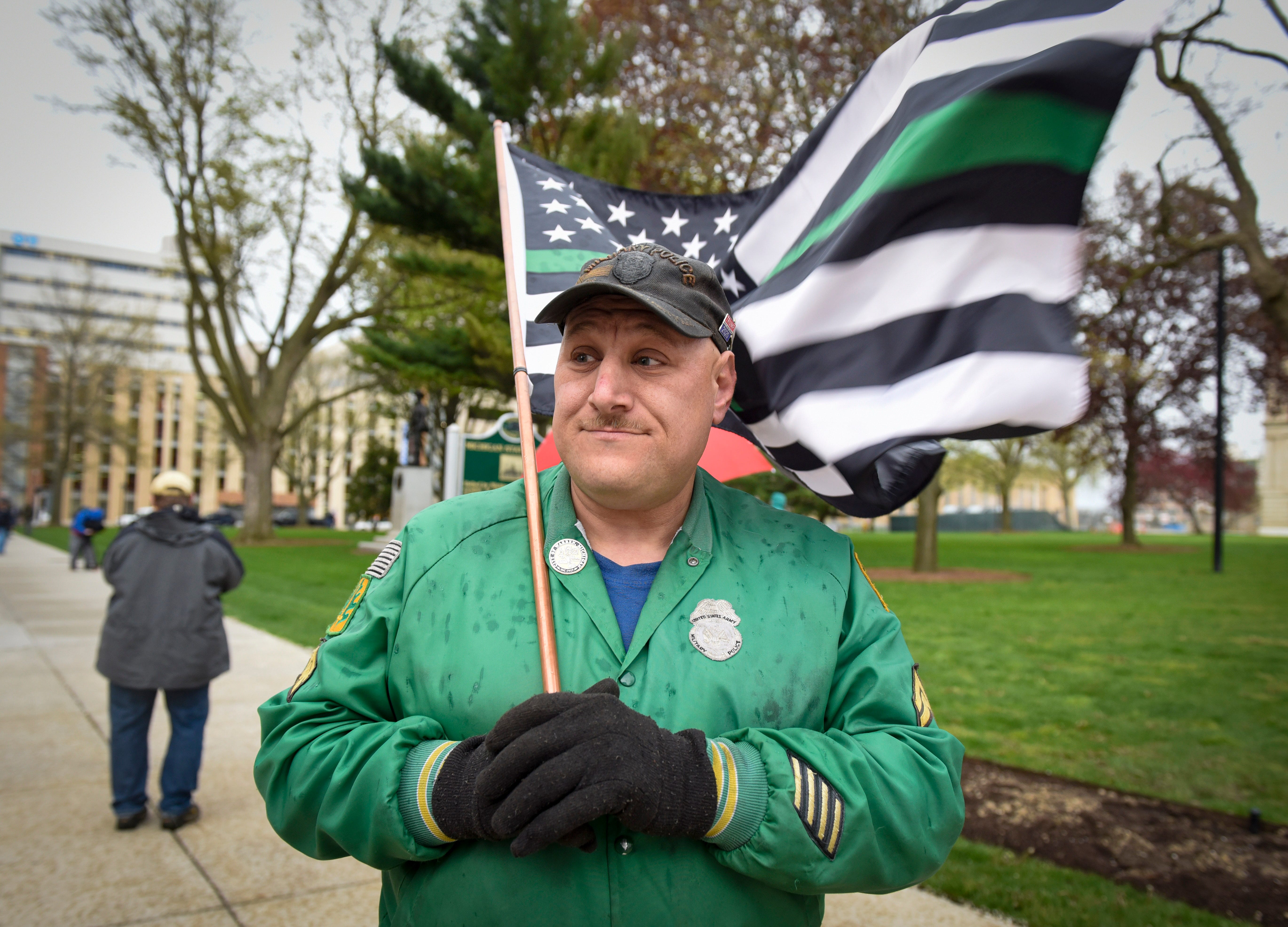 Warren city councilman Eddie Kabacinski holds a flag during a protest at the state Capitol to oppose the executive orders Gov. Gretchen Whitmer issued in response to the coronavirus pandemic, Thursday, May 14, 2020.