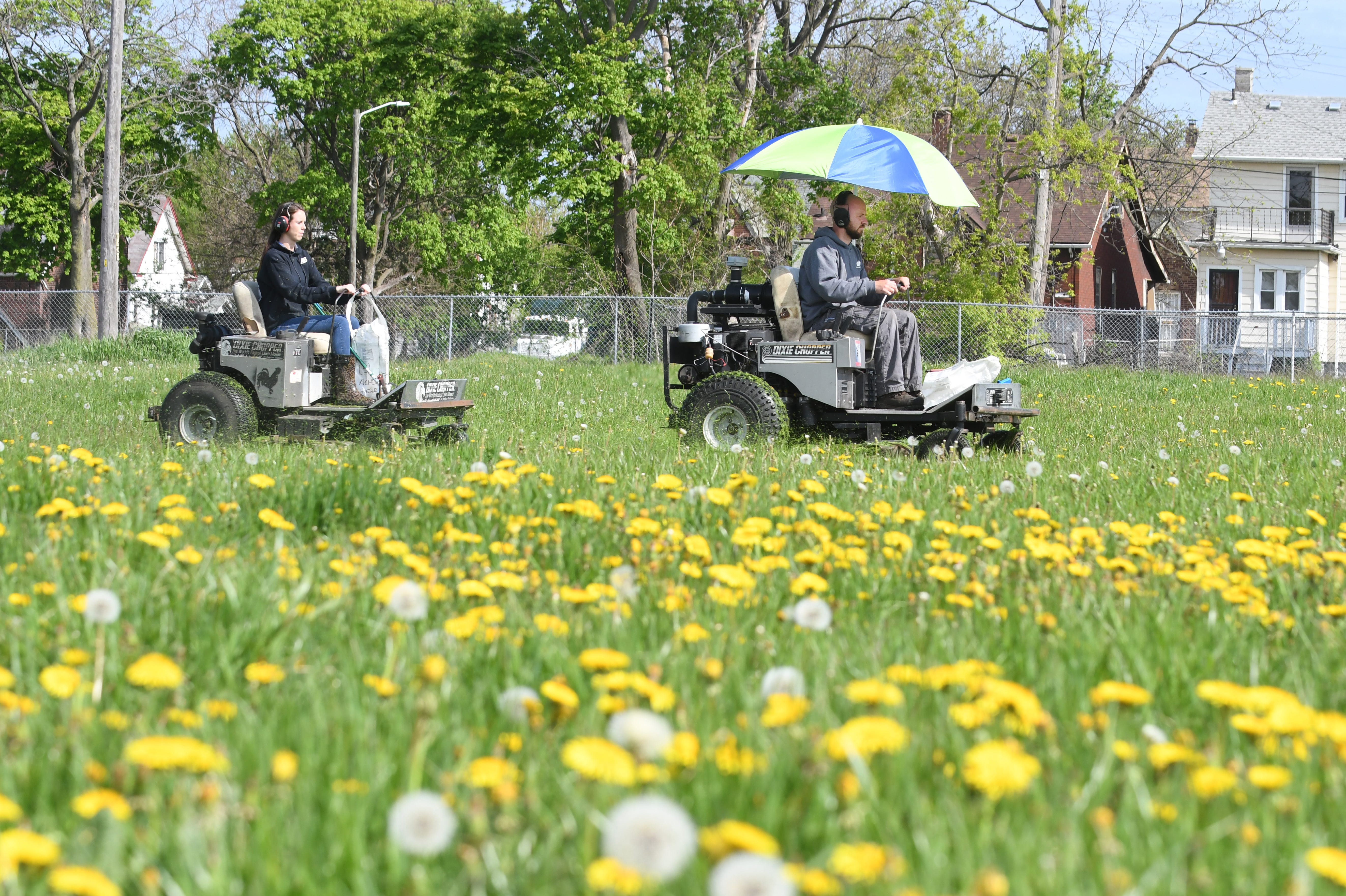 Hannah VanEckoute and her husband Gage of the Detroit Mower Gang start mowing the overgrown grass at Hammerberg Playfield in Detroit on Saturday, May 16, 2020.
