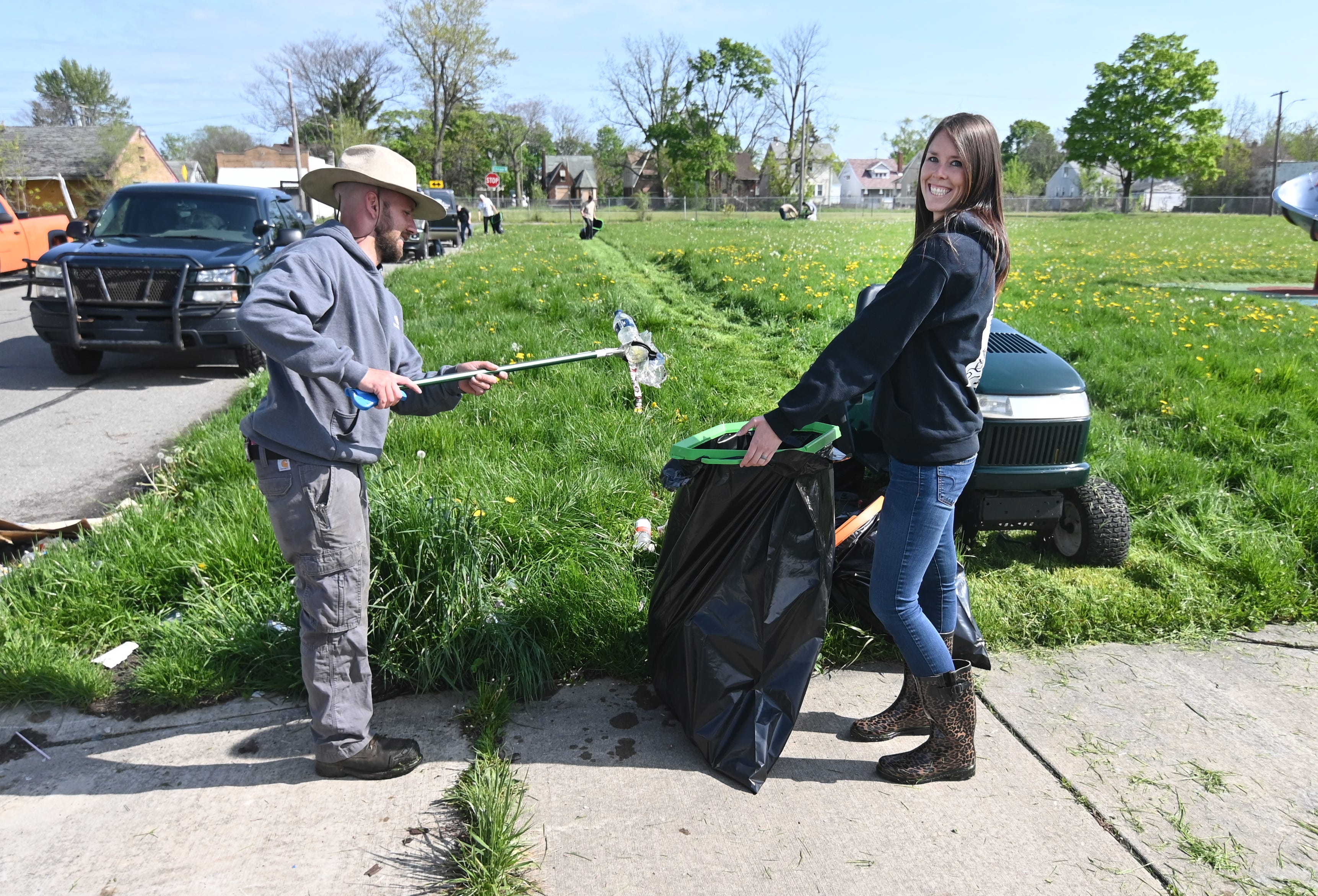 Gage VanEckoute, let, and his wife, Hannah VanEckoute, of the Detroit Mower Gang, pick up debris at Hammerberg Playfield in Detroit for the 2020 Motown Mowdown, a 12- hour mowing marathon.