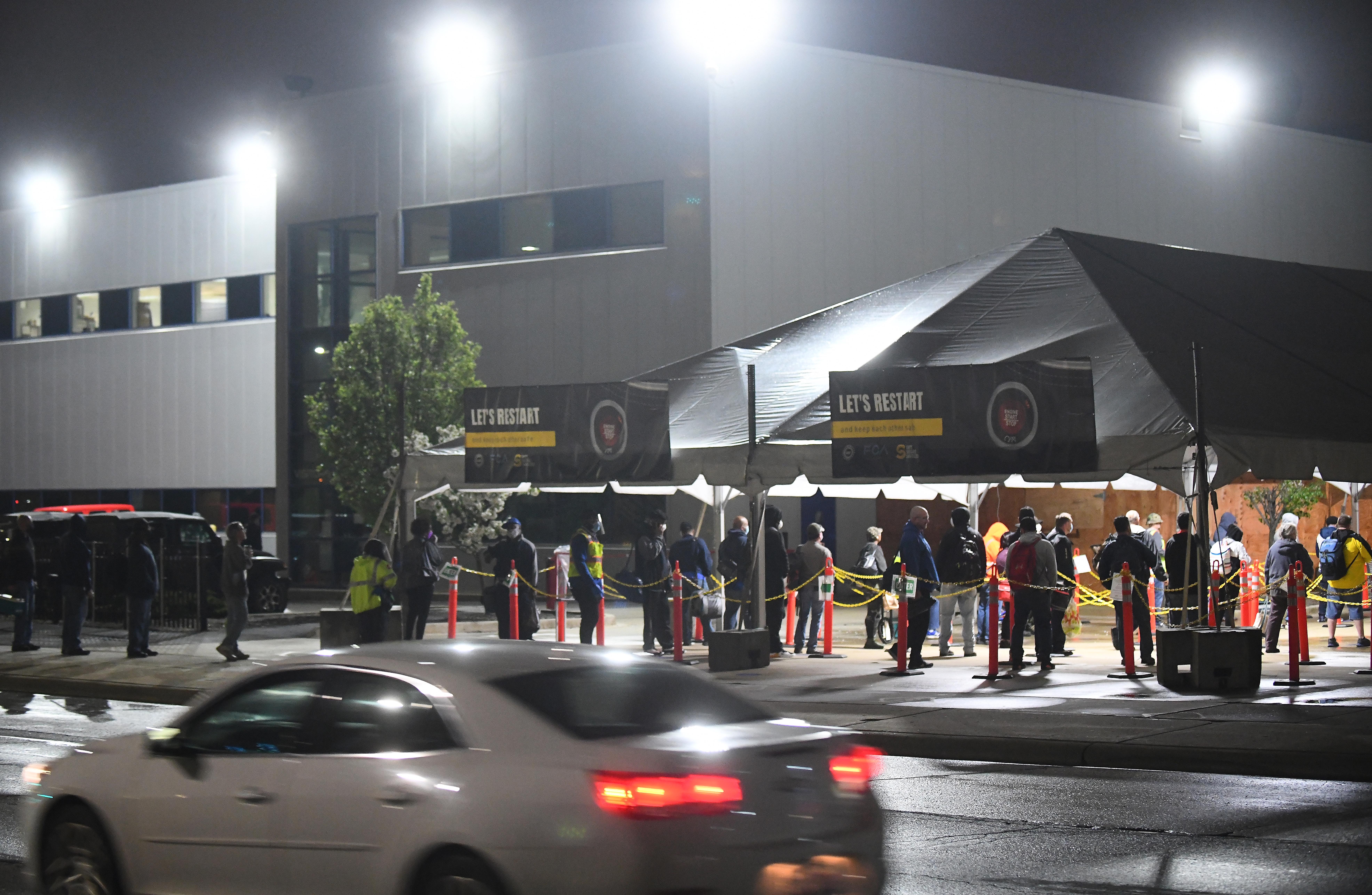 Employees wait in line at 4 a.m. as they arrive at the employee entrance at FCA Warren Truck Assembly in Warren, Michigan, on Monday, May 18, 2020.