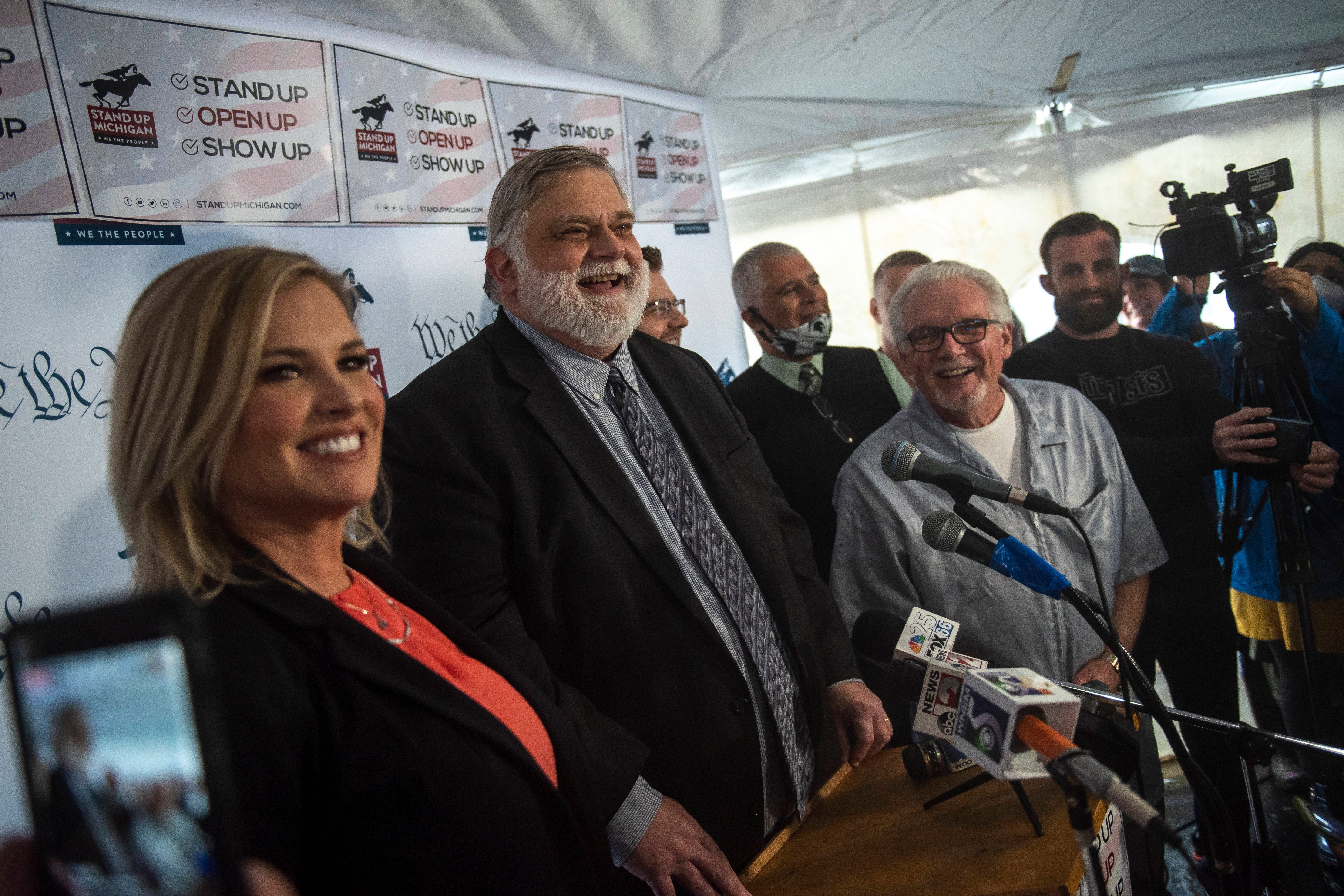 From left, North Dallas, Texas salon owner Shelley Luther, attorney David Kallman and barber Karl Manke smile at the press conference outside Karl's barbershop in Owosso.