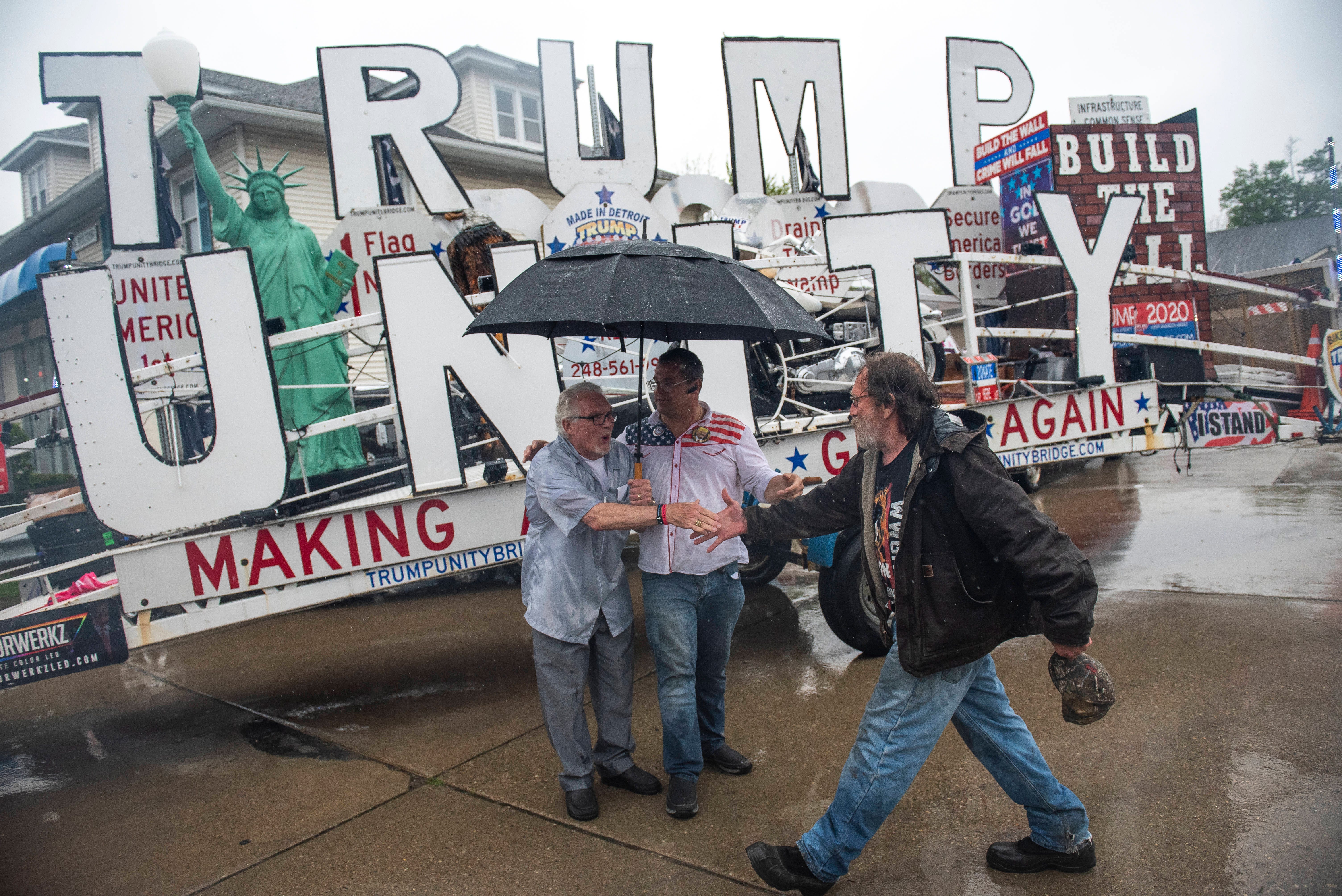 Owosso barber Karl Manke, left, reaches to shake hands with a supporter while posing for photos with Rob Cortis of Livonia, owner of the Trump Unity trailer.
