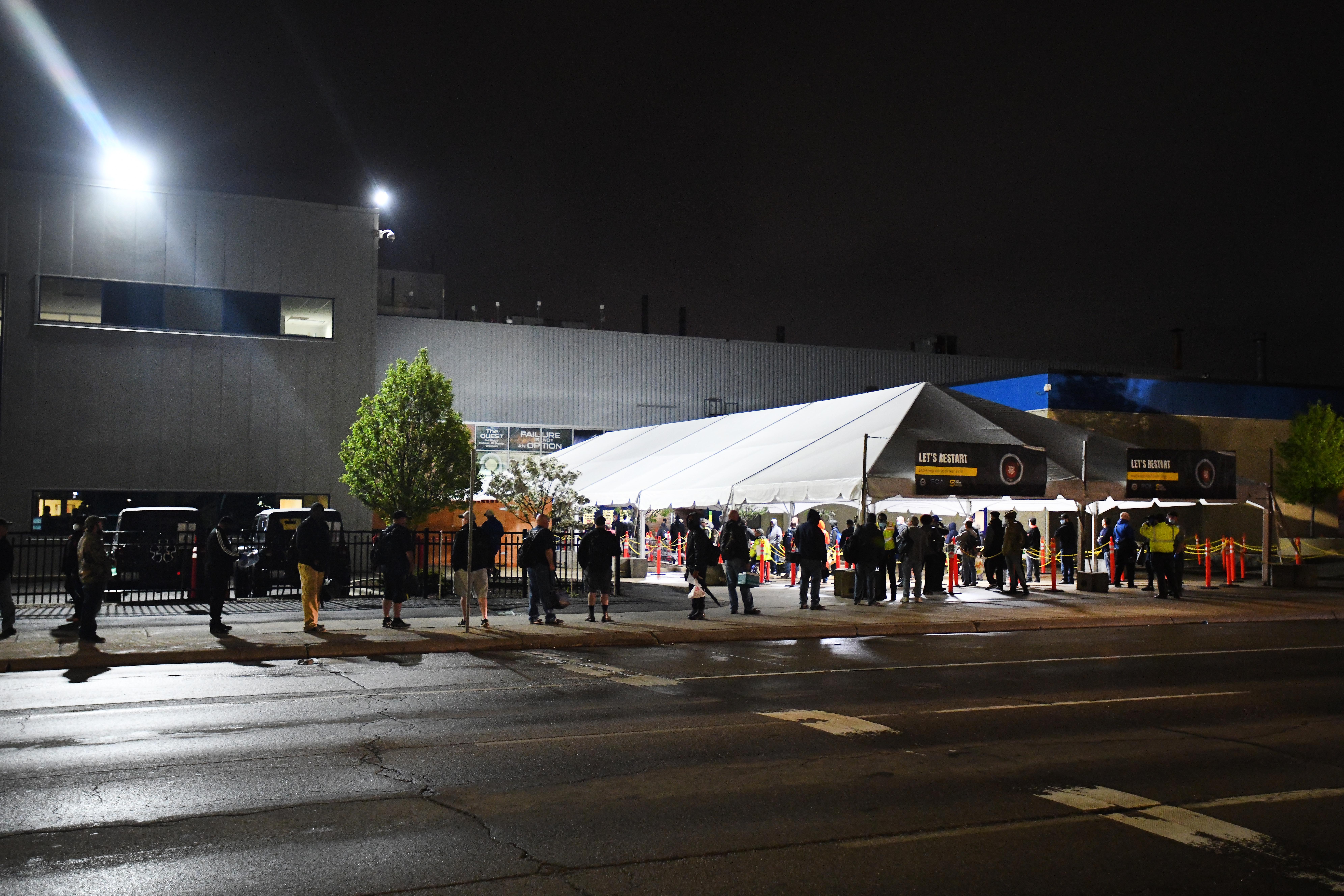 Employees wait in line at 4 am as they arrive at the employee entrance at FCA Warren Truck Assembly in Warren, Michigan, on Monday, May 18, 2020.