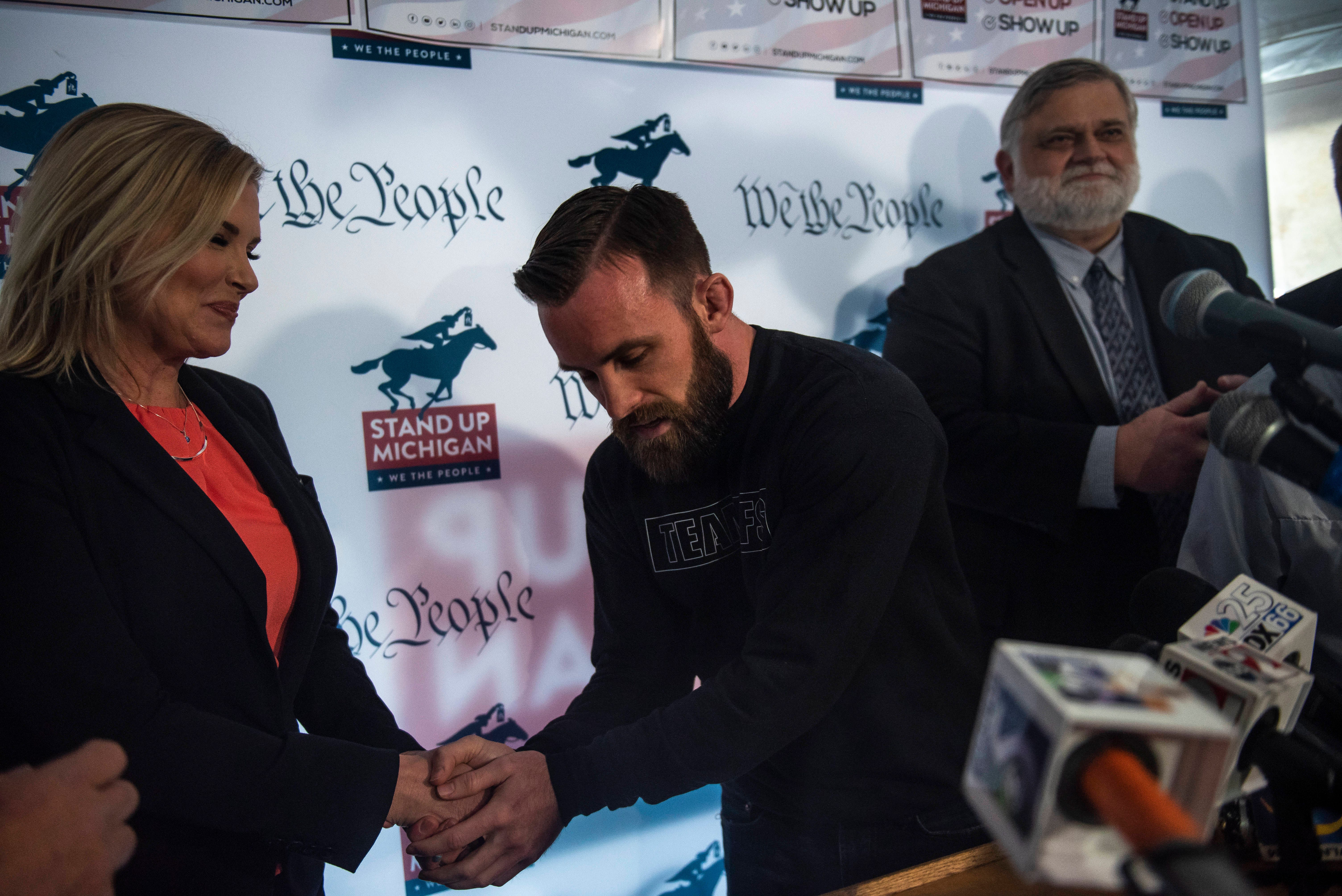 North Dallas, Texas salon owner Shelley Luther, left, and James Gray, owner of Michigan Institute Athletics in Brighton, Mich. shake hands during the press conference