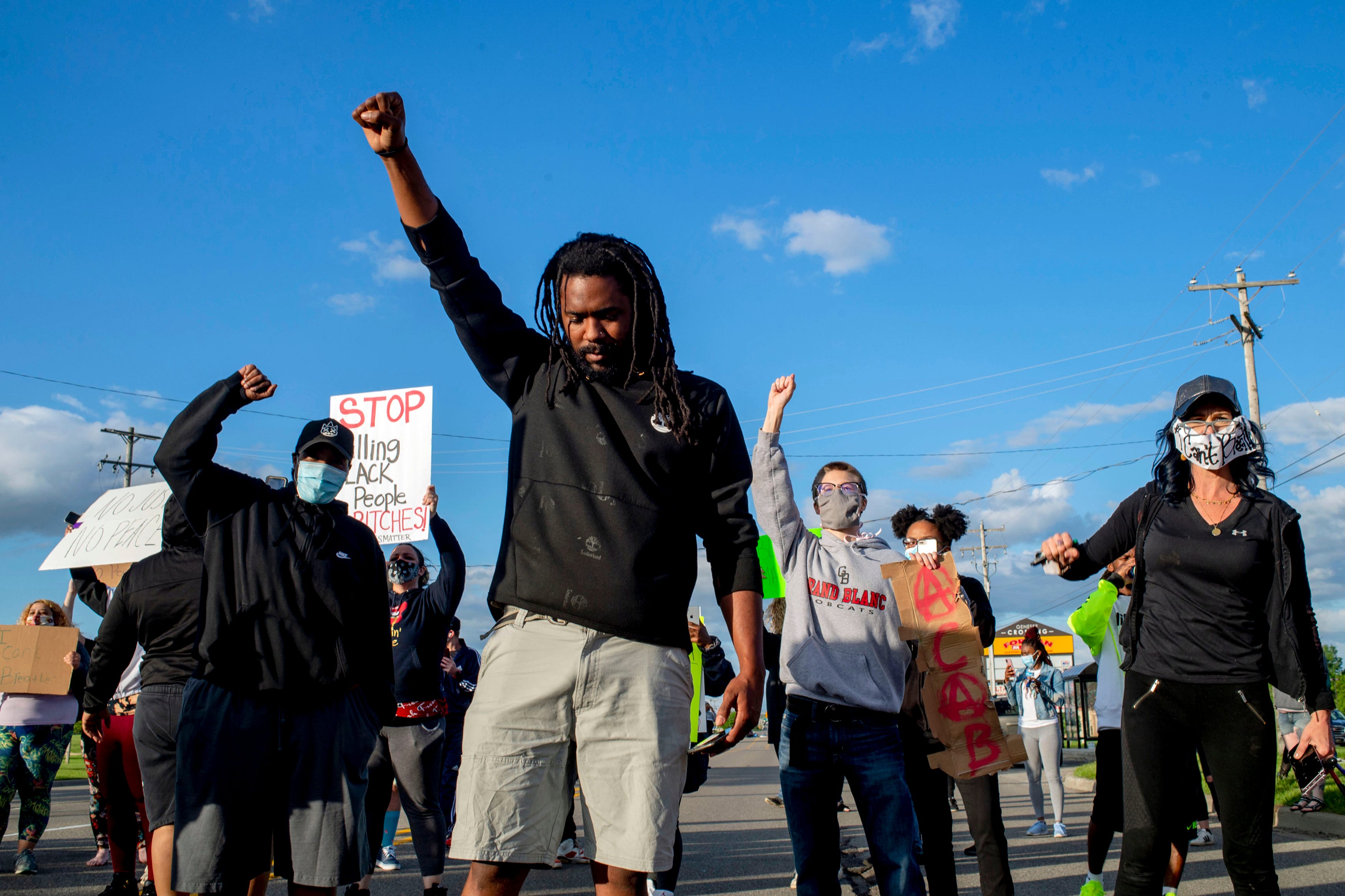 Flint resident Jawann Horton, 32, bows his head as he holds his fist to the sky as hundreds march at a peaceful protest seeking justice for George Floyd on Saturday, May 30, 2020 on Miller Road in Flint Township, M.I.  Floyd died in police custody on Memorial Day in Minneapolis.