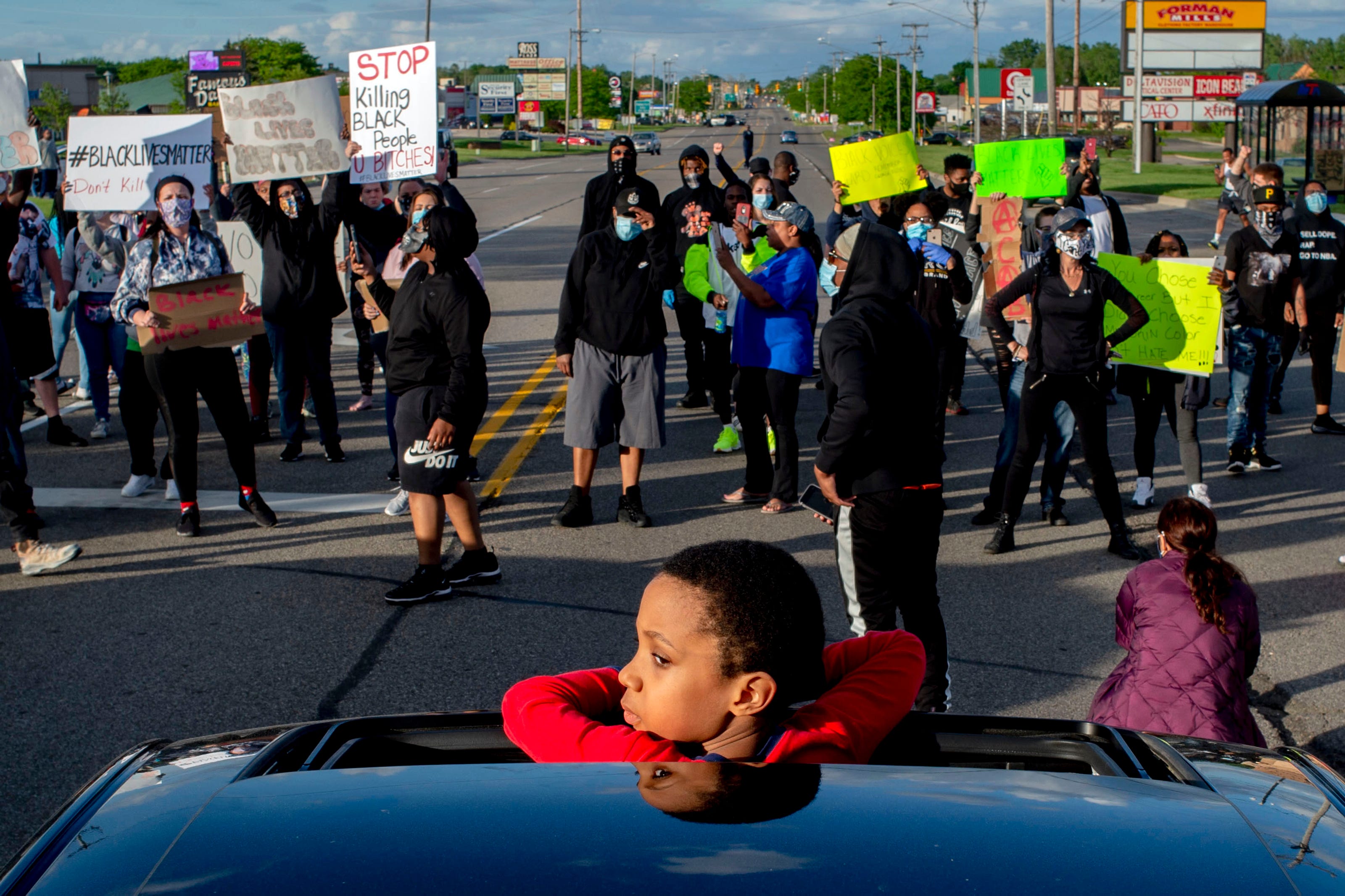 Ameer Watkins, 7, of Flint, looks out from a sunroof at the protest after his mother parked the car to join as hundreds march at peaceful protest seeking justice for George Floyd on Saturday, May 30, 2020 on Miller Road in Flint Township, M.I. Floyd died in police custody on Memorial Day in Minneapolis.