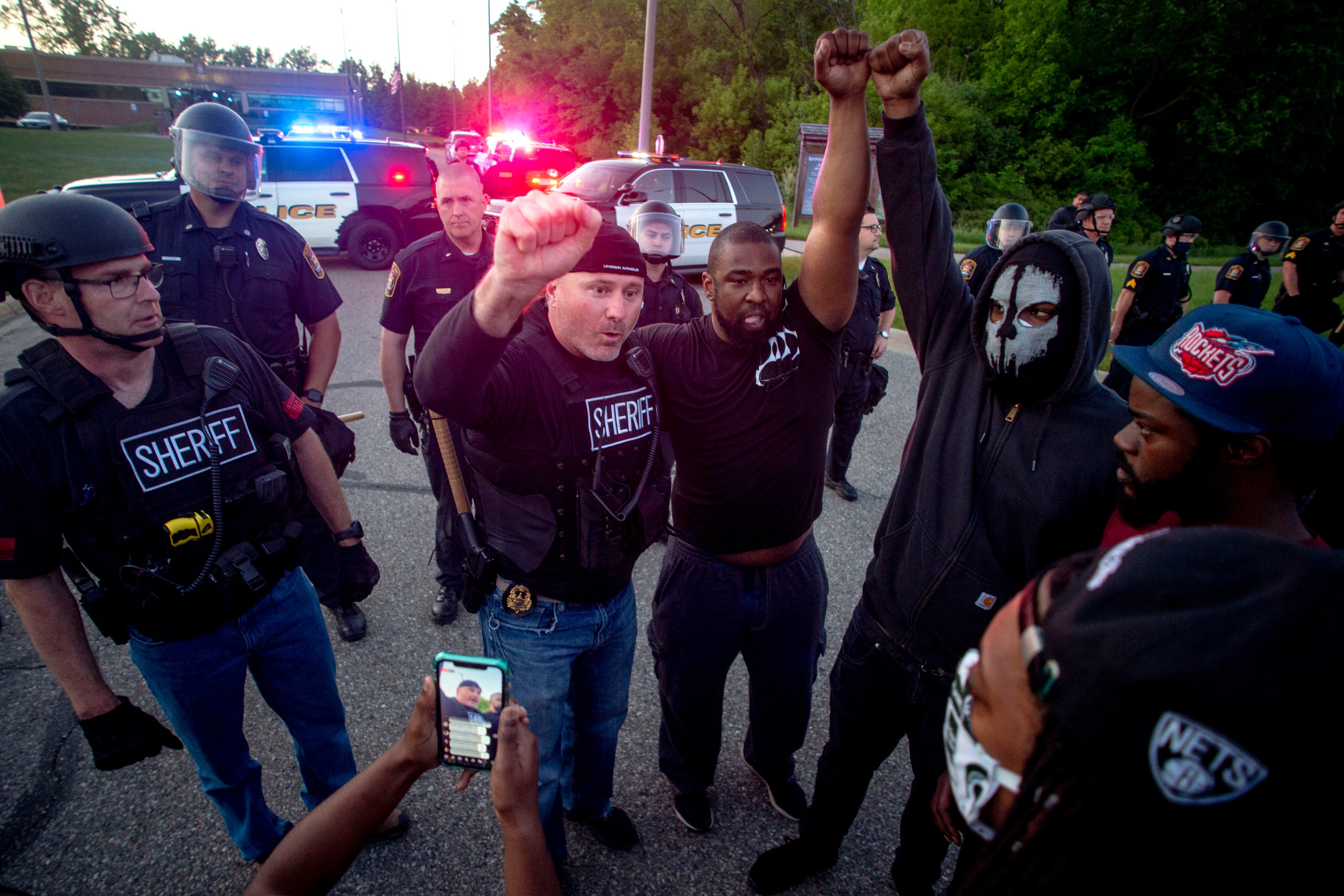 A Genesee County Sheriff's deputy raises his fist in solidarity alongside protesters as hundreds march at a peaceful protest seeking justice for George Floyd on Saturday, May 30, 2020, on Miller Road in Flint Township, M.I. Floyd died in police custody on Memorial Day in Minneapolis.