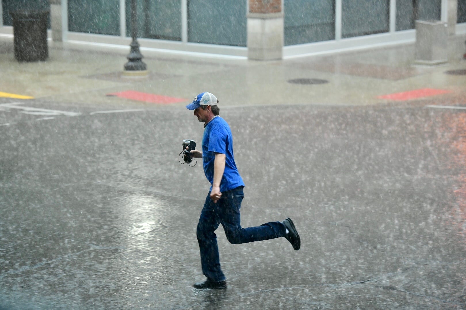 A pedestrian runs across the intersection of South Center Street and West Third Street during heavy rain in Royal Oak, June 10, 2020.