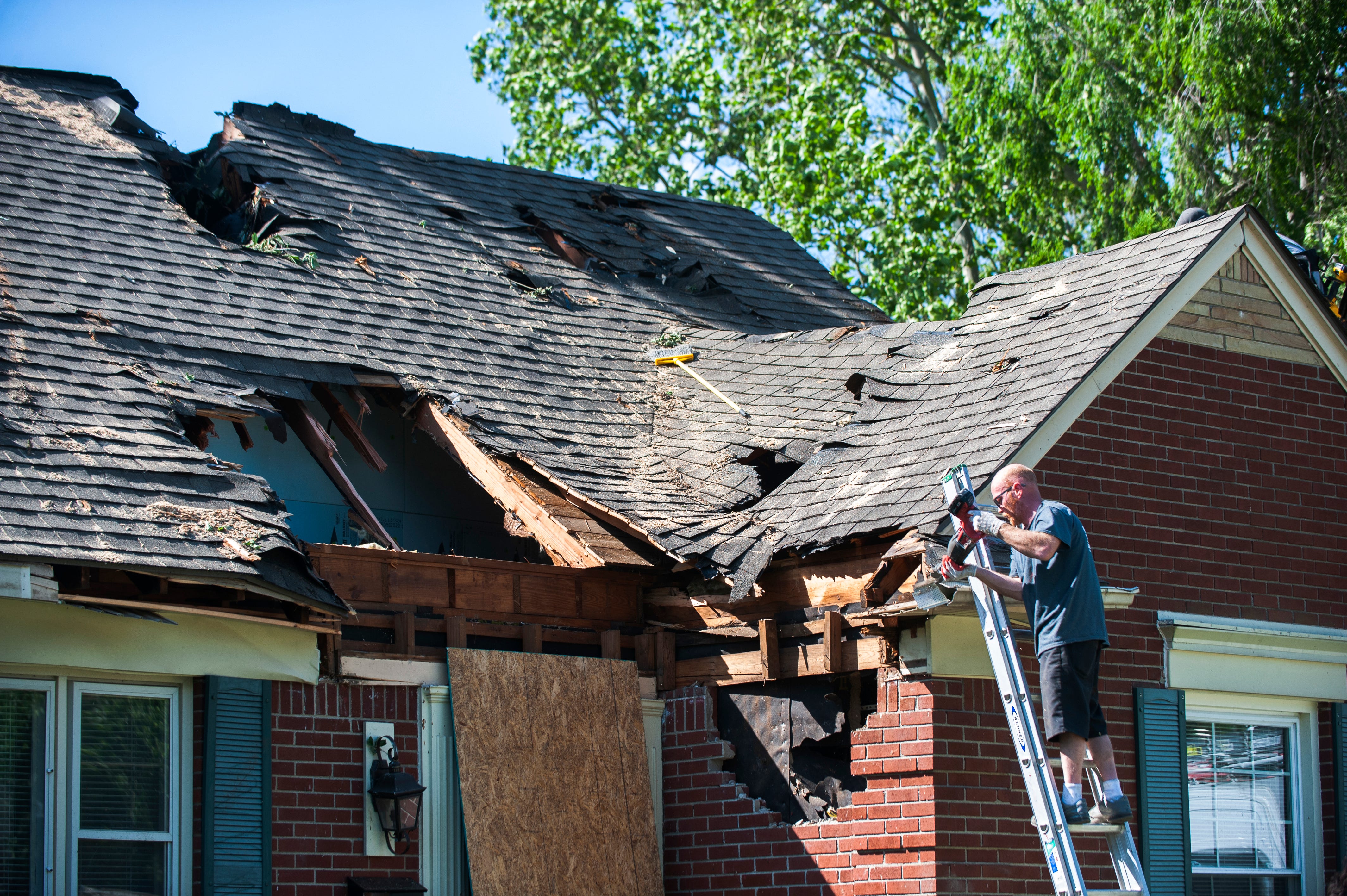 A crew from Bloomfield Construction work on the roof of Rebecca and Paul Tomezak's home in Grosse Pointe Woods that was extensively damaged when a wind-blown tree fell on it during Wednesday evening's storm.