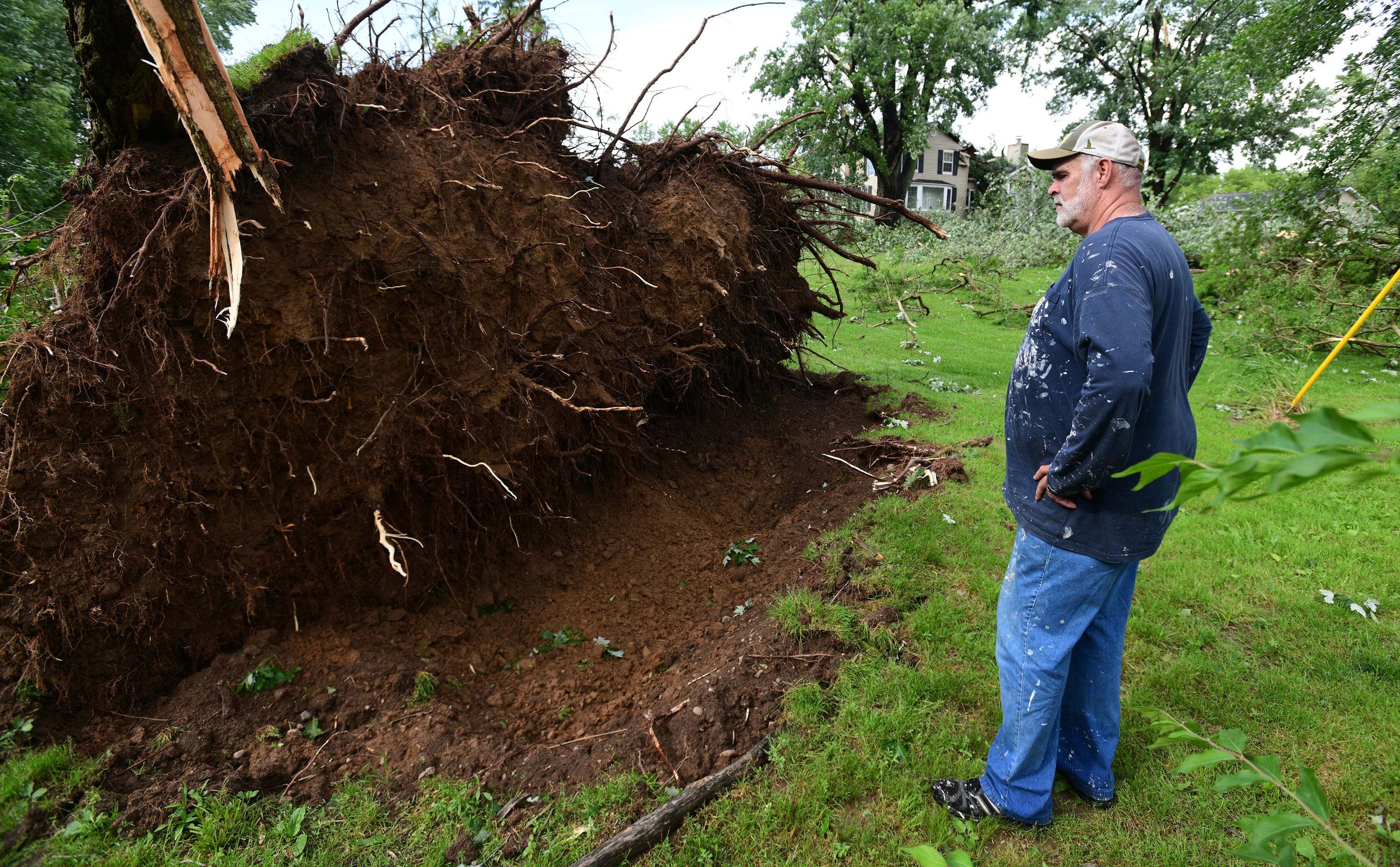 Tim Hinkle stands near the root ball of a downed tree on his property on King Road near Riegle Road on Wednesday, June 10, 2020. Strong storms with heavy winds swept across Jackson County, Mich., causing power outages, downing trees and damaging property. Hinkle had about a dozen trees either completely toppled or with limbs sent flying. His home also sustained damage.  (J. Scott Park/Jackson Citizen Patriot via AP)